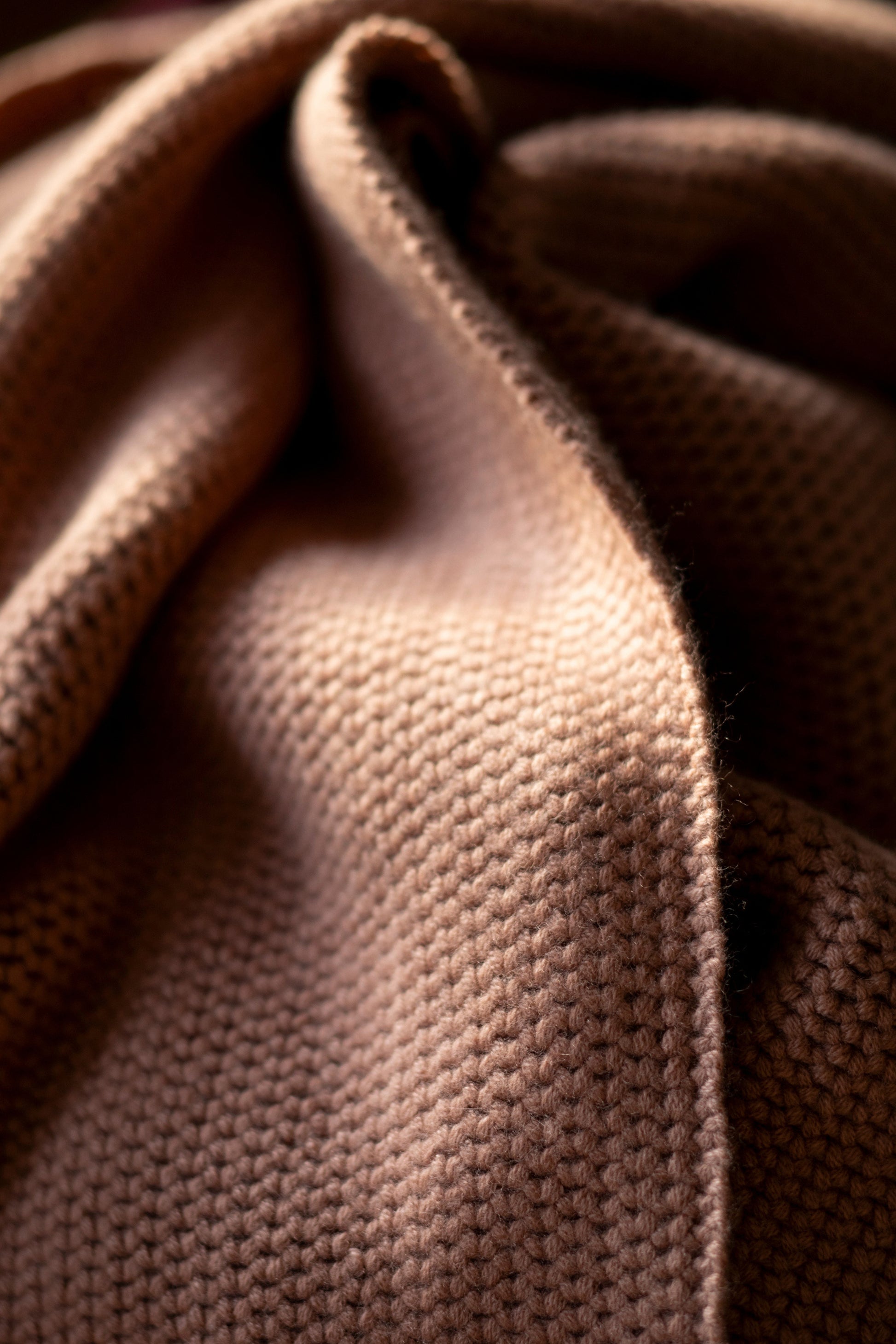 A model wearing the Mocha shawl.
 Achunky knit shawl made from 100% Mongolian cashmere. The shawl comes in a soft, muted shade of beige, enhancing its cozy and comforting appearance