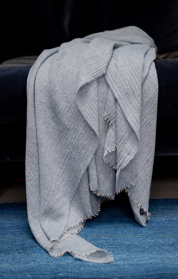 A light soft blue throw draped over a bed