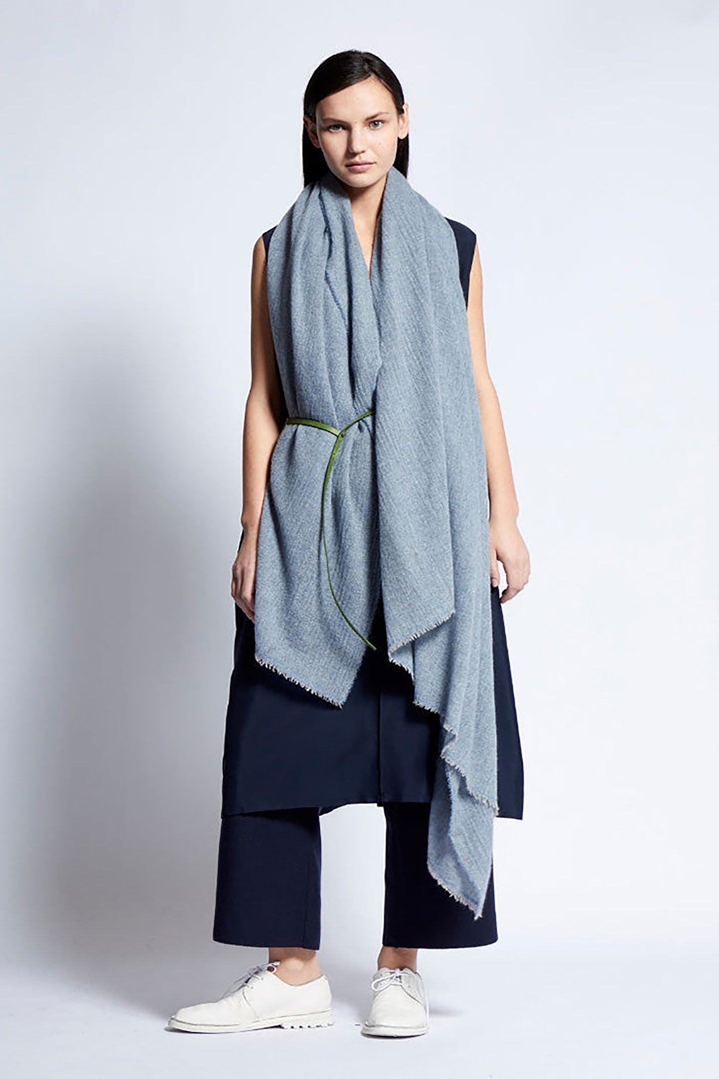 Woman wearing a long light blue throw with a white background