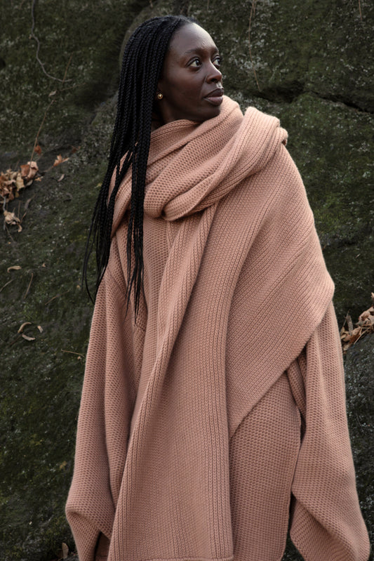 A model wearing the Mocha shawl.
 Achunky knit shawl made from 100% Mongolian cashmere. The shawl comes in a soft, muted shade of beige, enhancing its cozy and comforting appearance