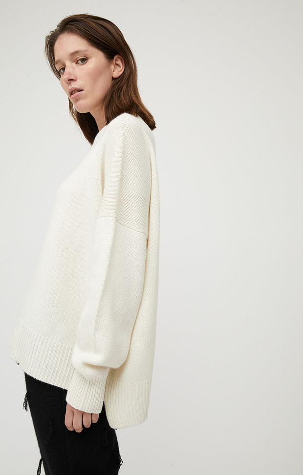 Woman wearing Alia oversized fit cashmere sweater in colour Ivory.  The cashmere sweater is knitted in a single jersey stitch. 