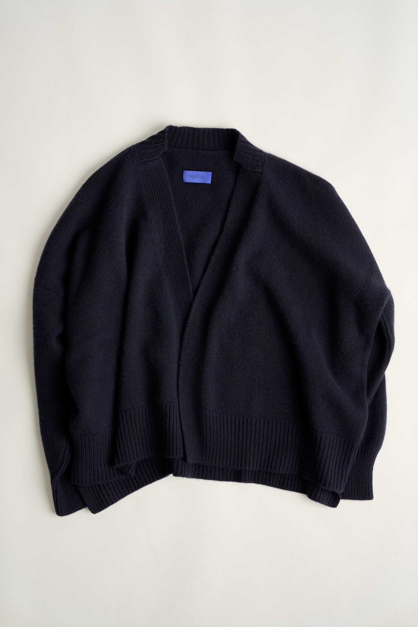 This image features the Aire Cardigan, a luxurious, chunky open cardigan made from pure cashmere. The cardigan is displayed laying flat on a white background.