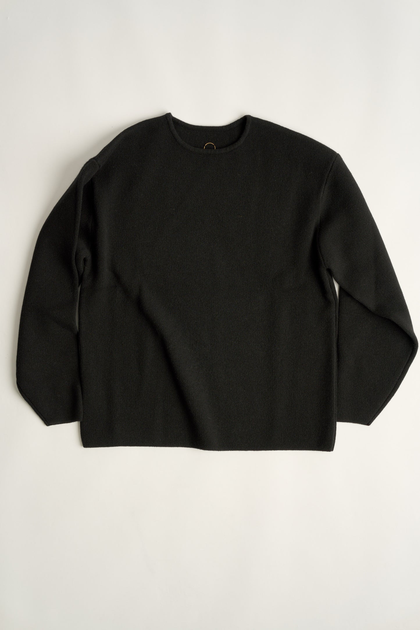 This image features the Axa Sweater, highlighted in a minimalistic style with a black color. The sweater showcases an oversized fit with distinct drop shoulders and sculpted, rounded sleeves.