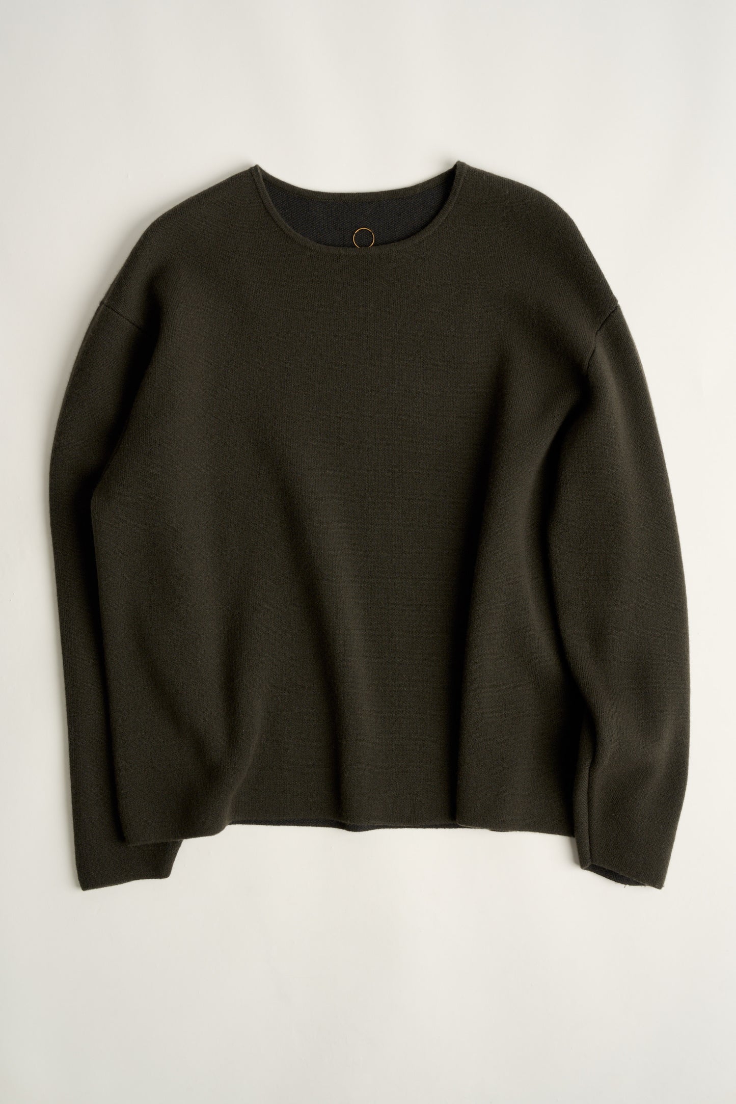 This image features the Axa Sweater, highlighted in a minimalistic style with a forest color. The sweater showcases an oversized fit with distinct drop shoulders and sculpted, rounded sleeves.