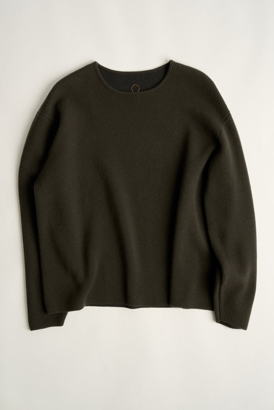 This image features the Axa Sweater, highlighted in a minimalistic style with a forest color. The sweater showcases an oversized fit with distinct drop shoulders and sculpted, rounded sleeves.