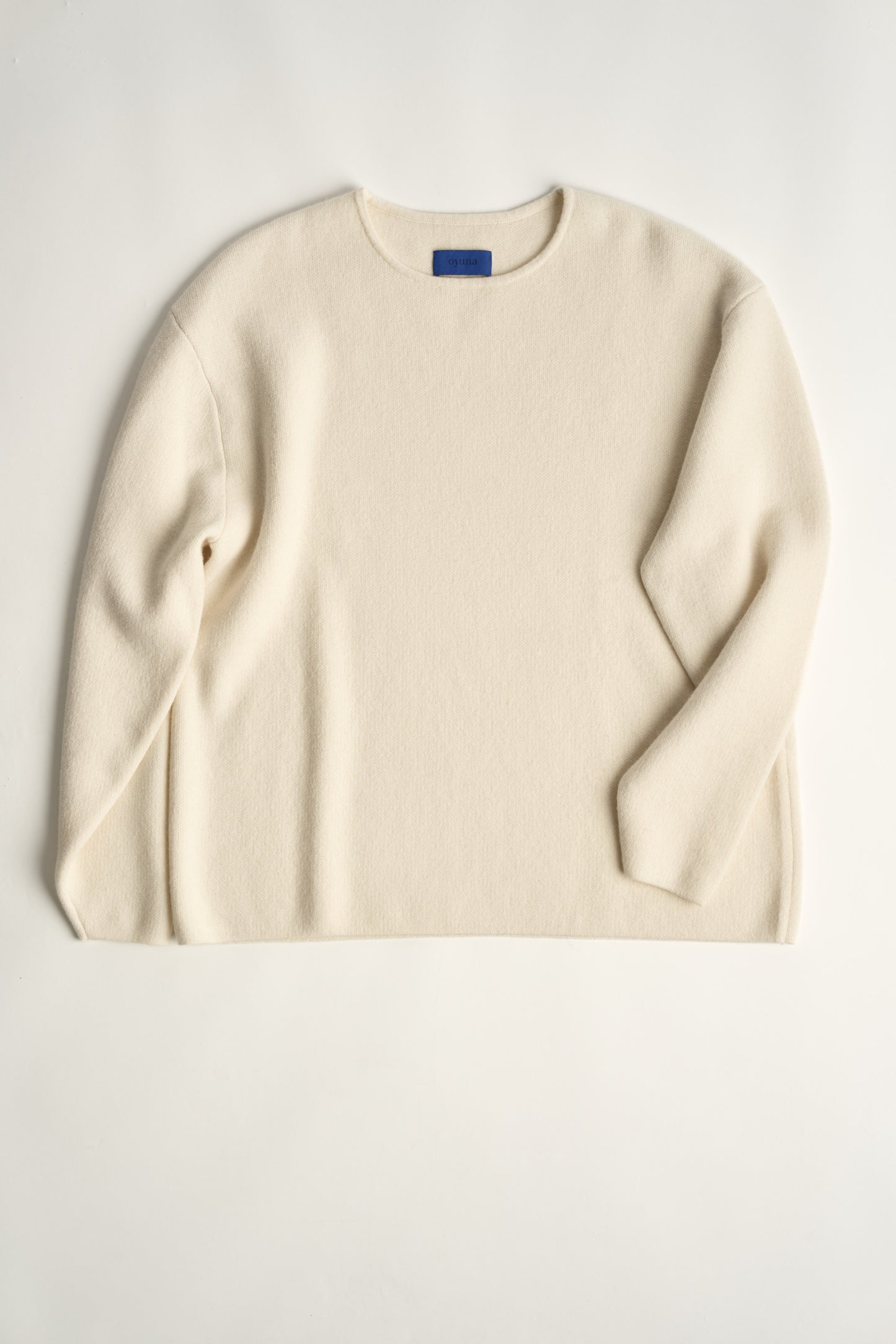 This image features the Axa Sweater, a stylish and comfortable piece that showcases an oversized fit with drop shoulders and sculpted, rounded sleeves. The sweater is knitted using a structured jacquard stitch, which adds texture and depth to its appearance.