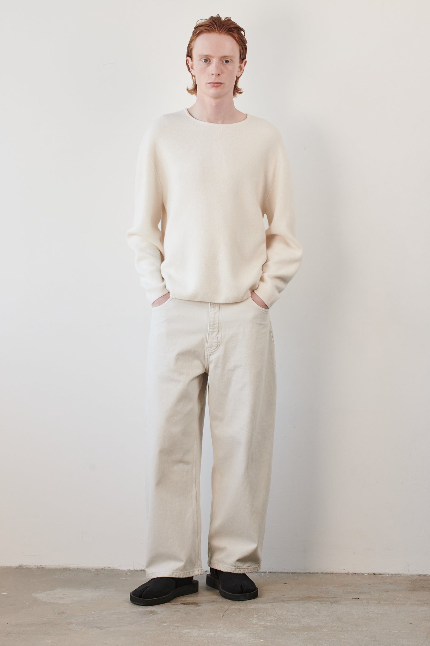 This image features the Axa Sweater, highlighted in a minimalistic style with a ivory color. The sweater showcases an oversized fit with distinct drop shoulders and sculpted, rounded sleeves.