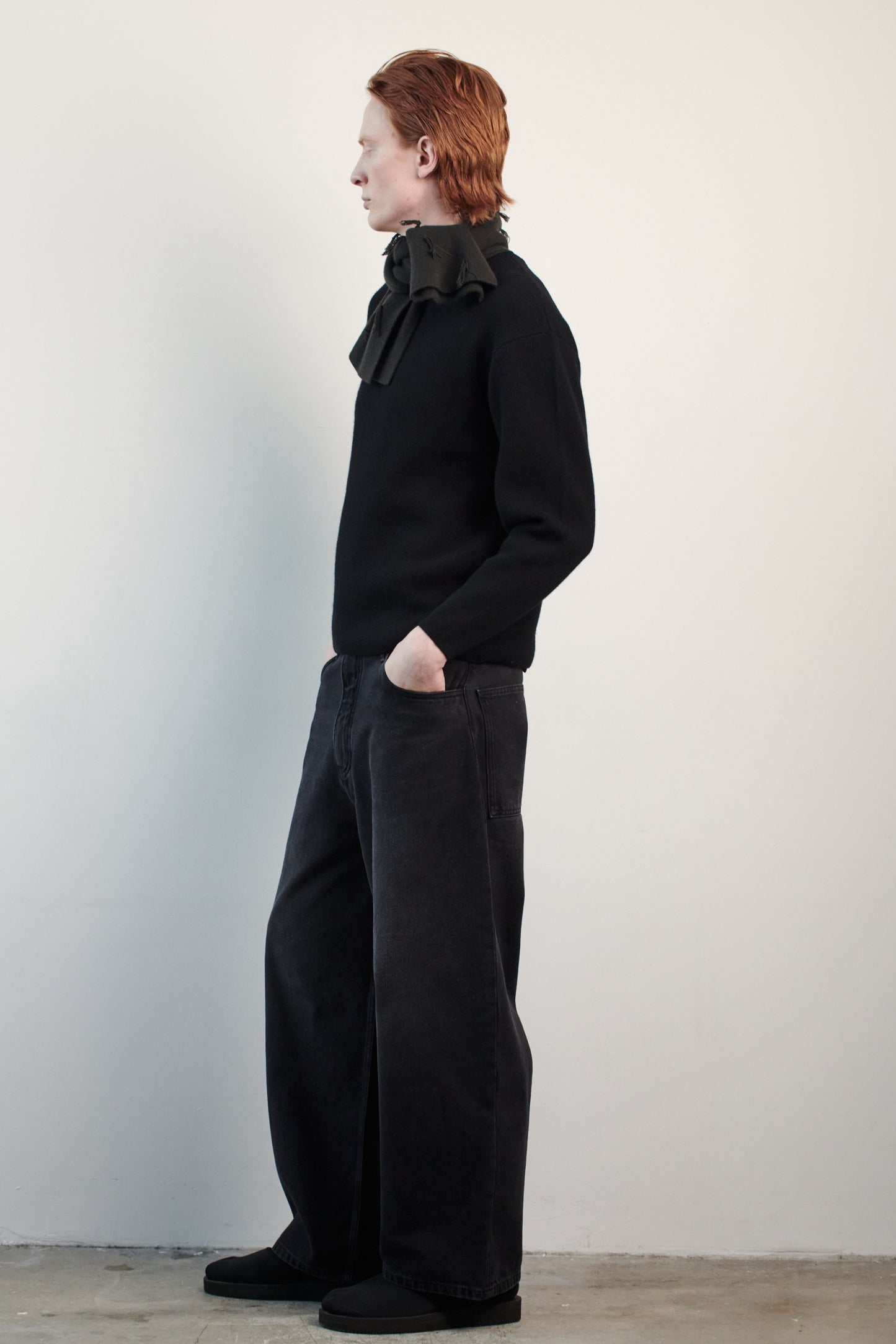 This image features the Axa Sweater, highlighted in a minimalistic style with a black color. The sweater showcases an oversized fit with distinct drop shoulders and sculpted, rounded sleeves.