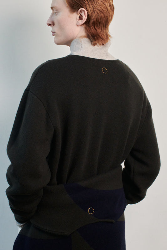 This image features the Axa Sweater, highlighted in a minimalistic style with a forest color. The sweater showcases an oversized fit with distinct drop shoulders and sculpted, rounded sleeves.