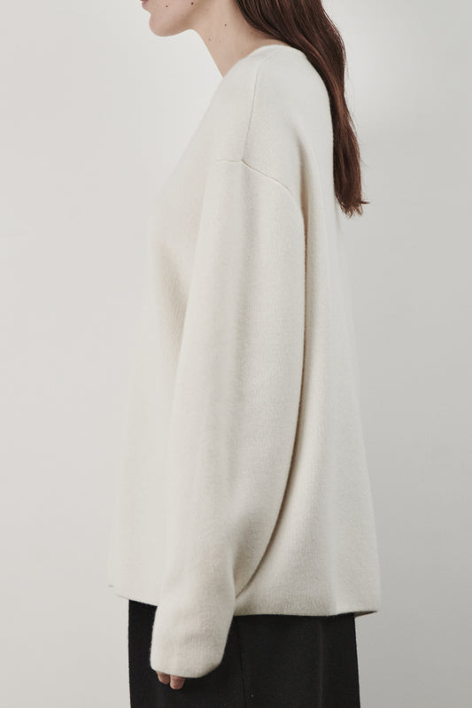 This image features the Axa Sweater, a stylish and comfortable piece that showcases an oversized fit with drop shoulders and sculpted, rounded sleeves. The sweater is knitted using a structured jacquard stitch, which adds texture and depth to its appearance.