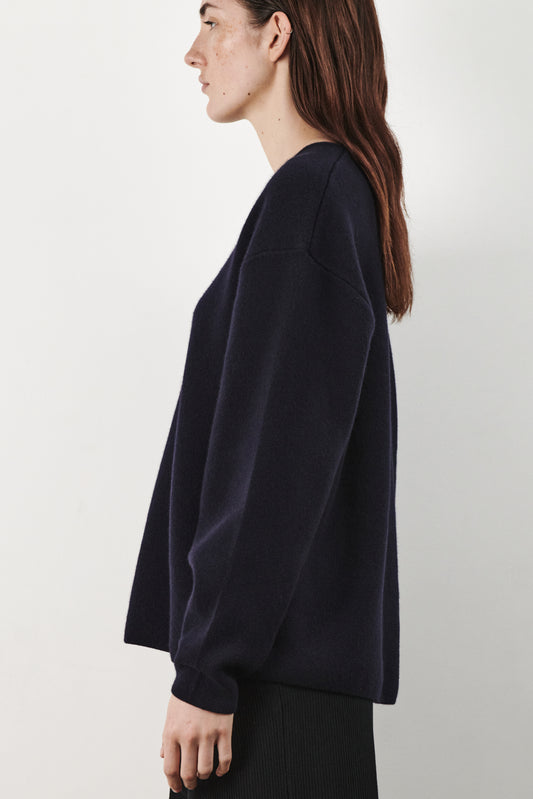 This image features the Axa Sweater, a stylish and comfortable piece that showcases an oversized fit with drop shoulders and sculpted, rounded sleeves. The sweater is knitted using a structured jacquard stitch, which adds texture and depth to its appearance.