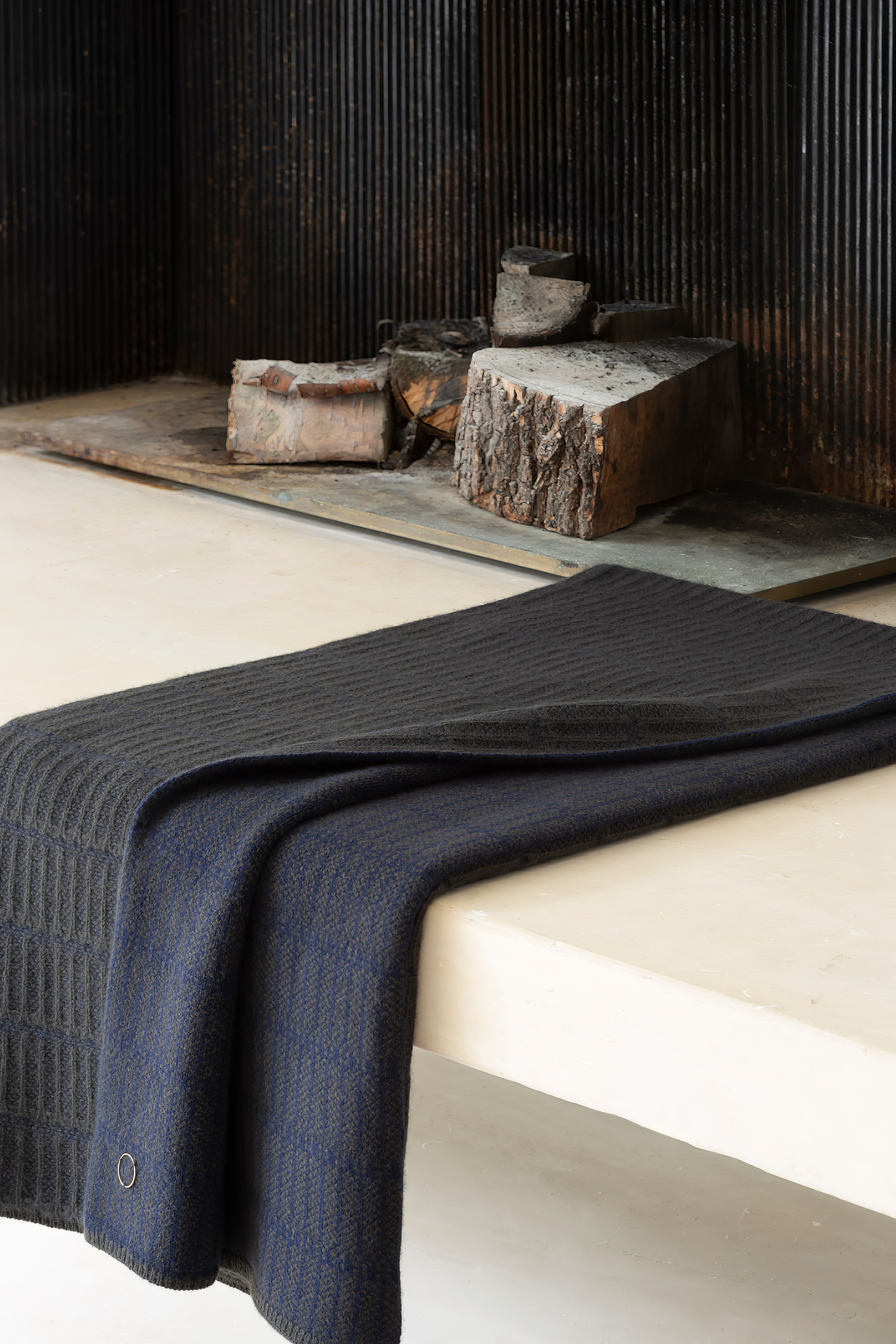 A throw blanket with a simple geometric pattern laid out on a flat surface, showcasing alternating vertical lines in two colors.