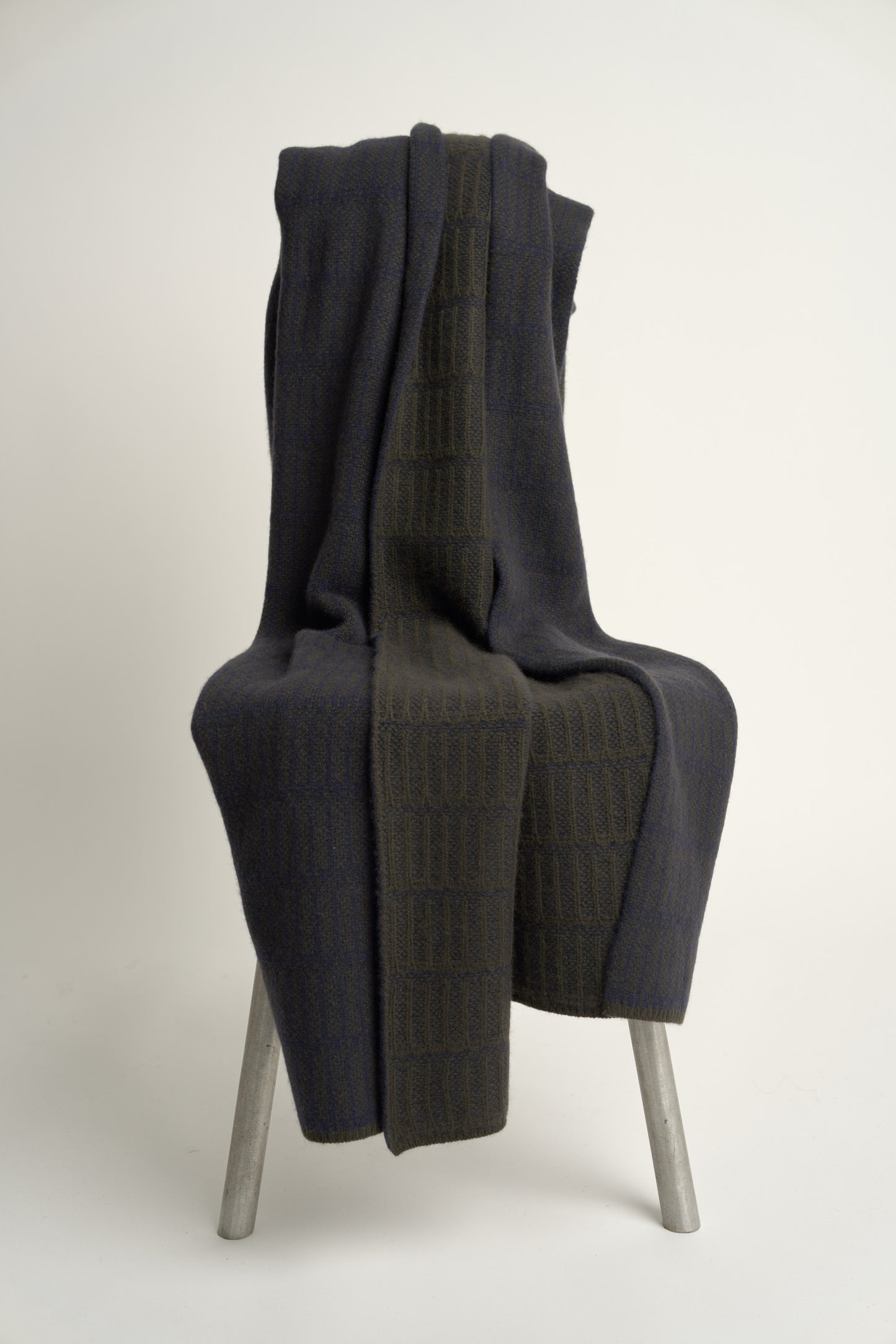 A throw blanket with a simple geometric pattern laid out on a flat surface, showcasing alternating vertical lines in two colors.