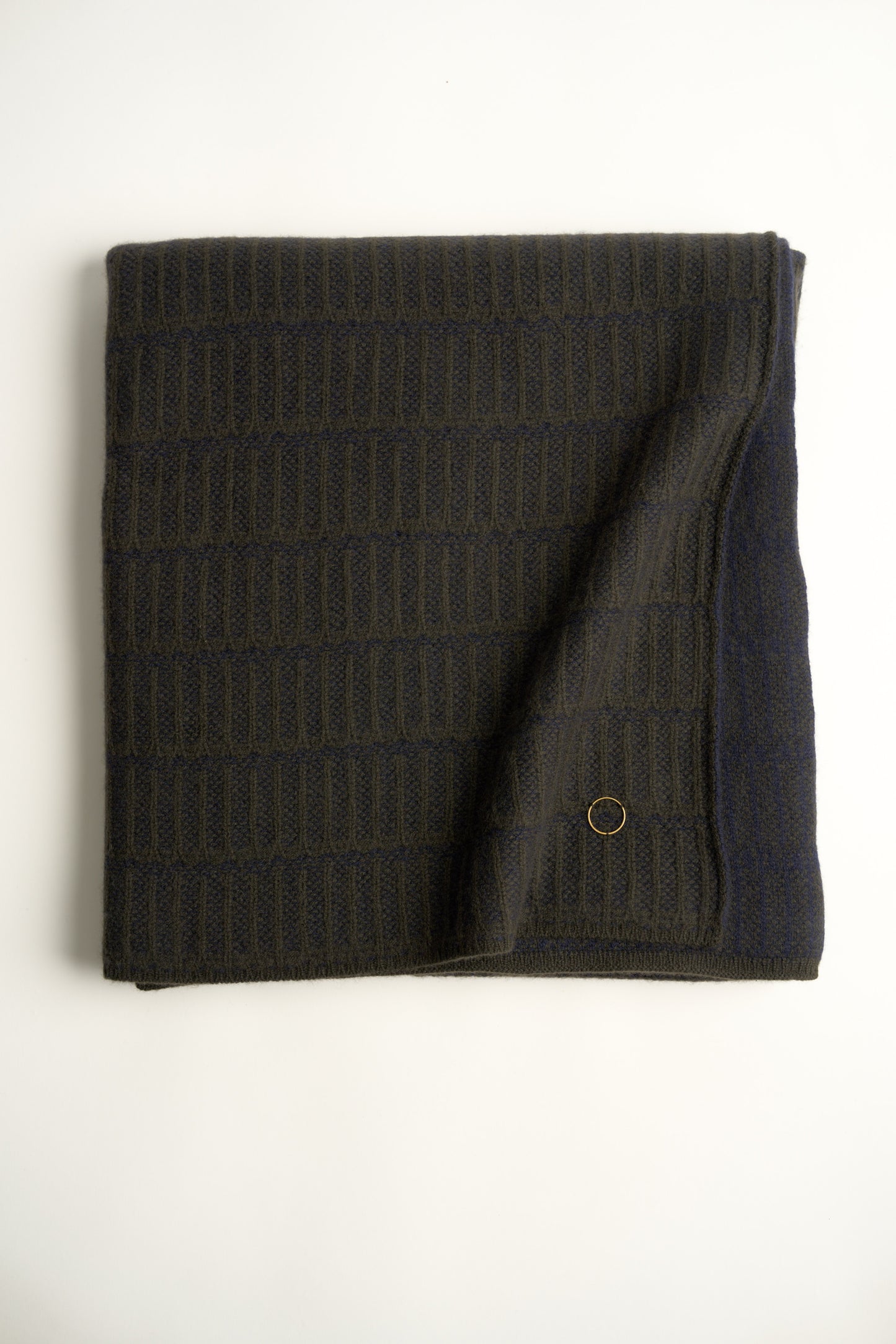 A throw blanket with a simple geometric pattern laid out on a flat surface, showcasing alternating vertical lines in two colors.