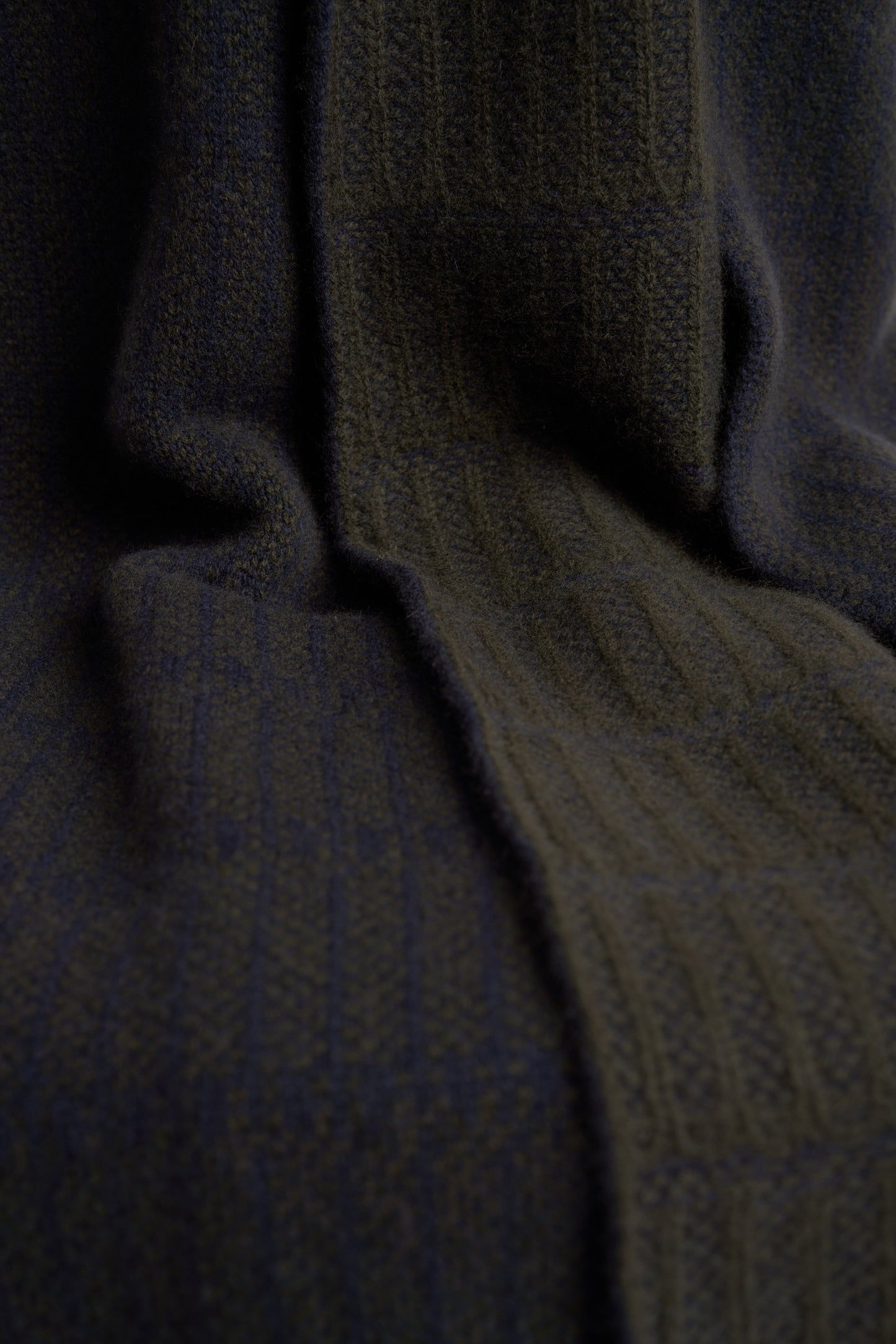 A throw blanket with a simple geometric pattern laid out on a flat surface, showcasing alternating vertical lines in two colors.