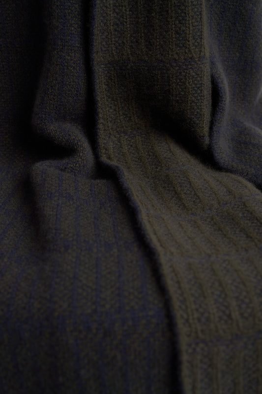 A throw blanket with a simple geometric pattern laid out on a flat surface, showcasing alternating vertical lines in two colors.