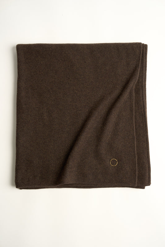 A chocolate throw draped over a chair, against a white background.