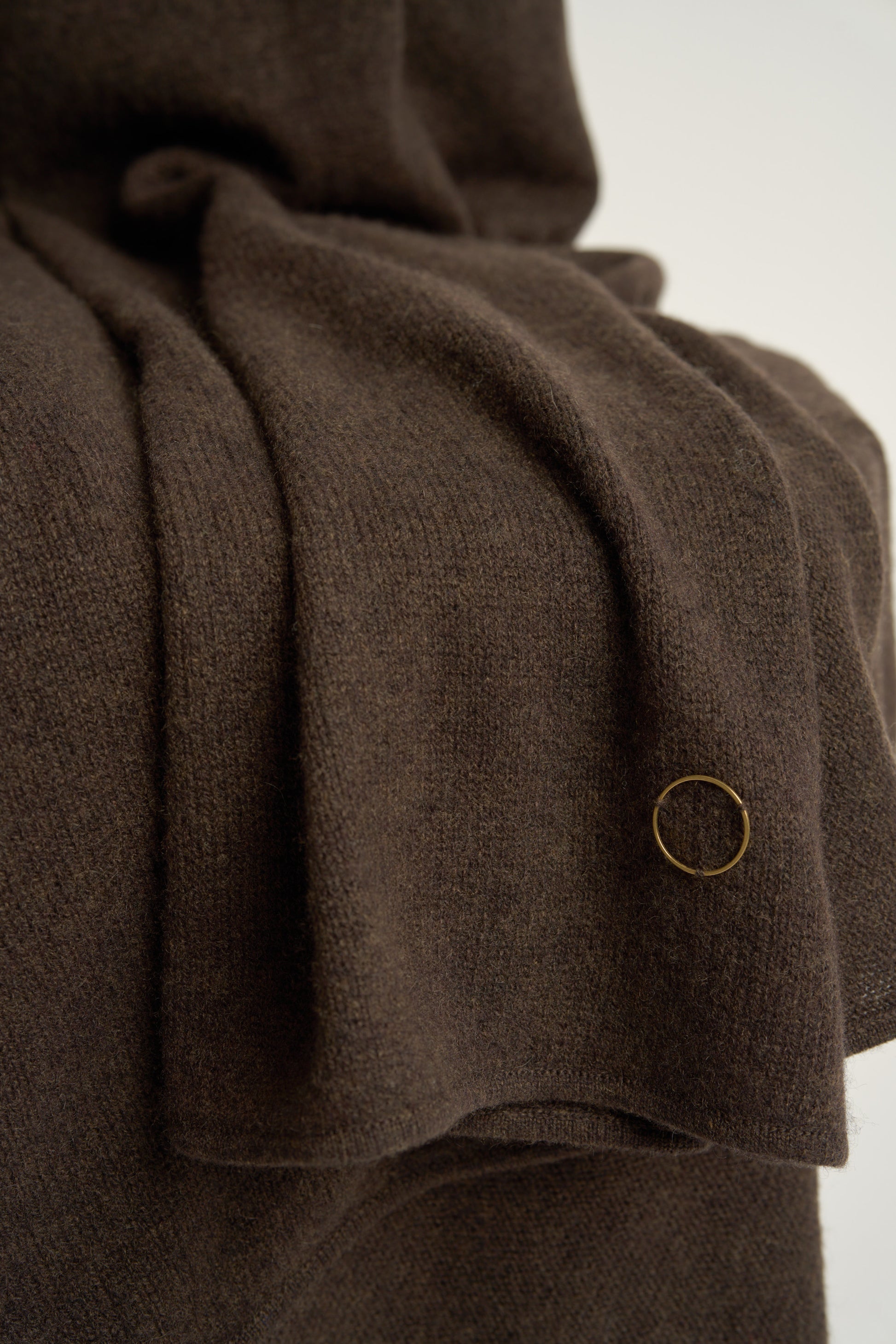 A chocolate throw draped over a chair, against a white background.