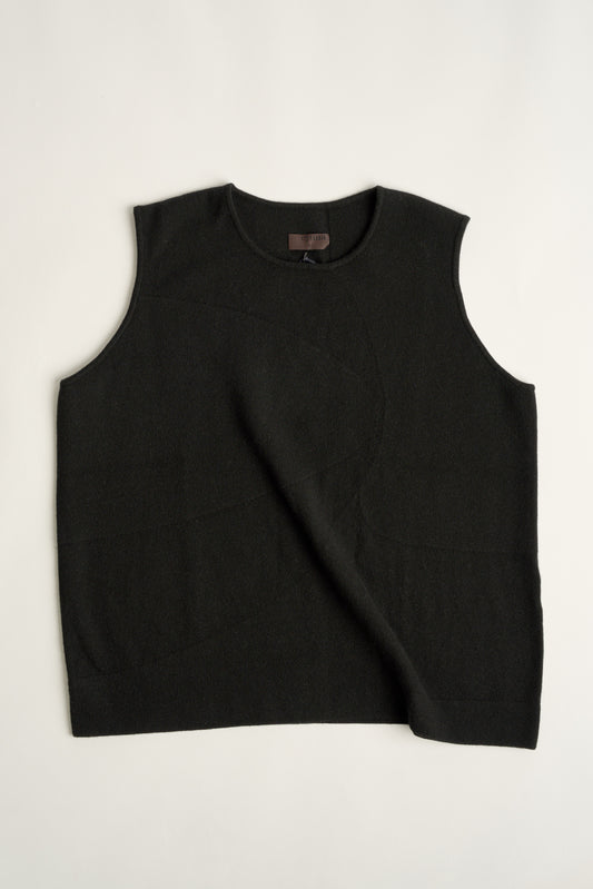 This image features the Duon Top, a stylish and comfortable cashmere knit vest in a subtle black color. The vest is designed with a boxy silhouette and fitted shoulders, creating a relaxed yet fitted look.