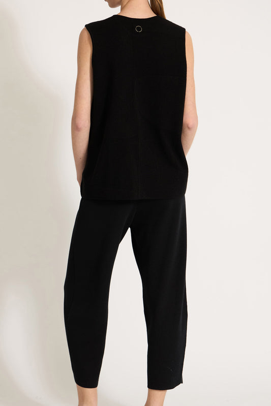 This image features the Duon Top, a stylish and comfortable cashmere knit vest in a subtle black color. The vest is designed with a boxy silhouette and fitted shoulders, creating a relaxed yet fitted look.