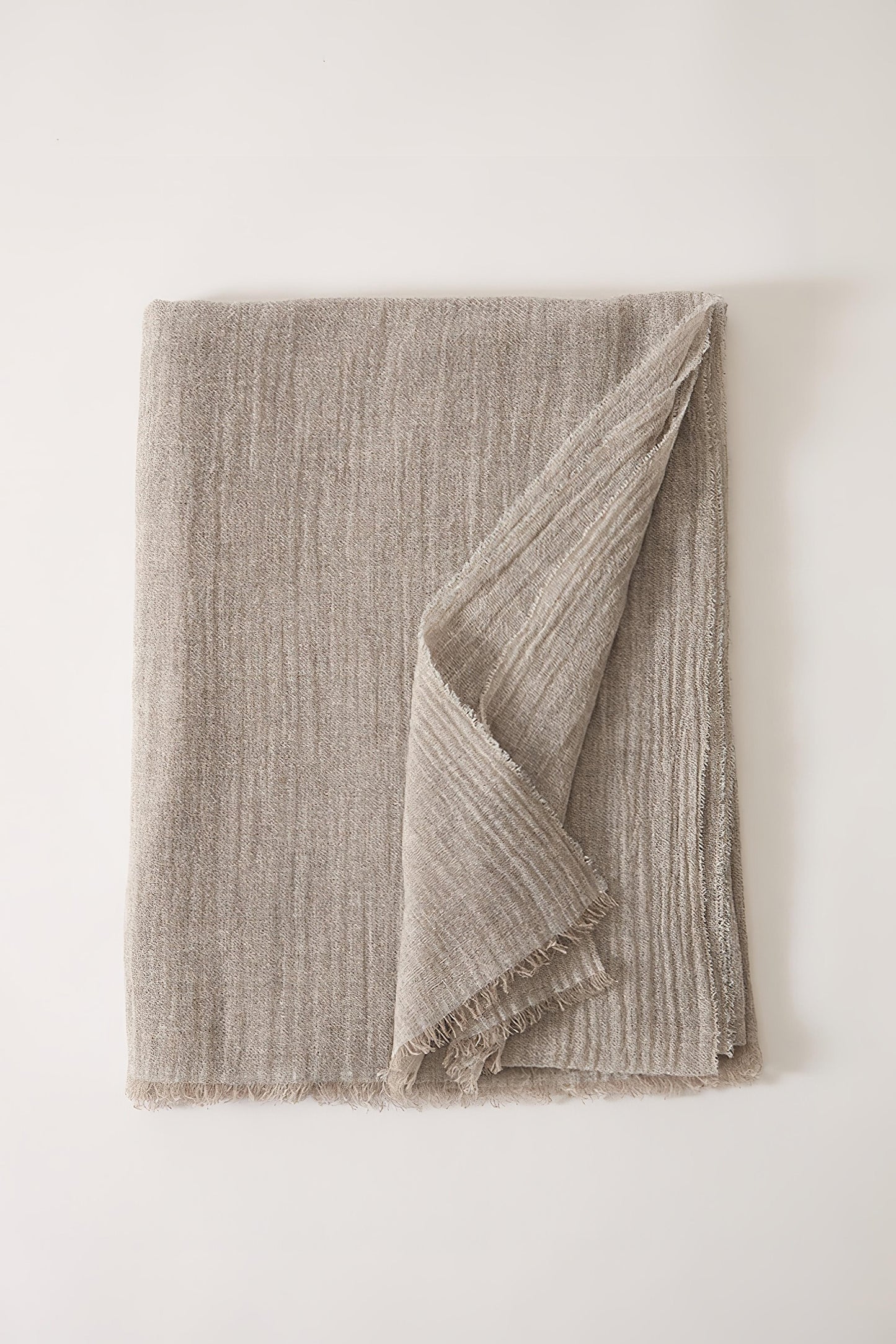 A folded Esra mist coloured throw on a white background