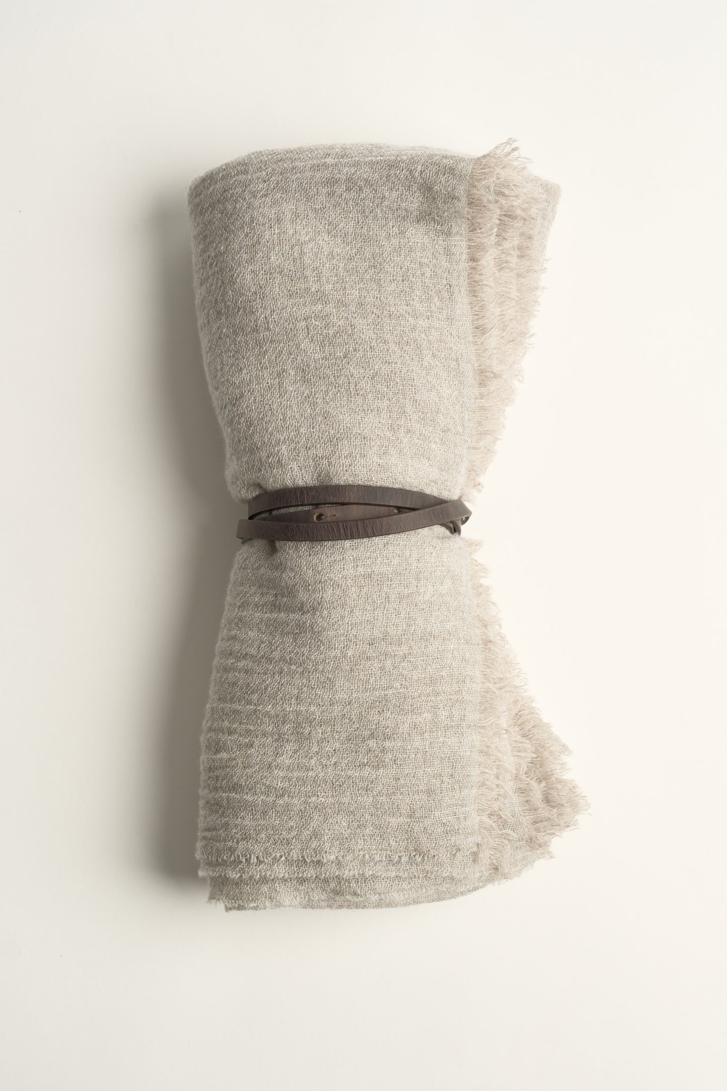 An Esra mist coloured throw on a white background with a brown belt