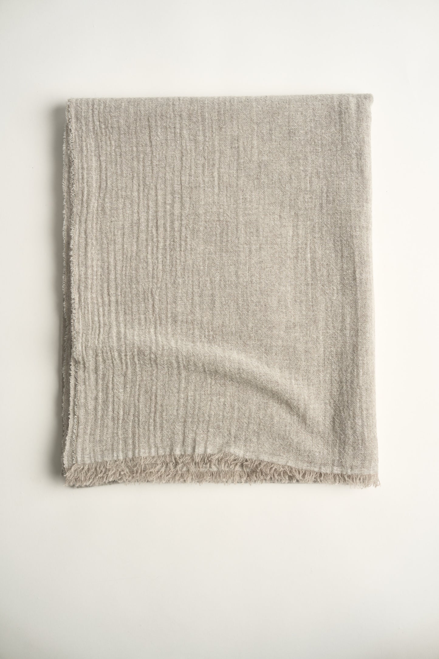 A natural light colour cashmere throw with a soft, airy weave, displayed on a plain background.