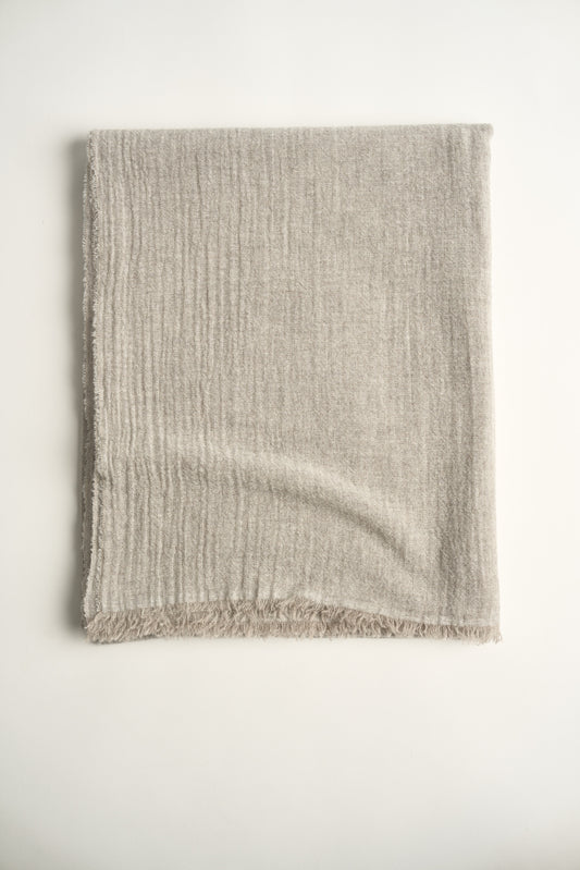 A natural light colour cashmere throw with a soft, airy weave, displayed on a plain background.