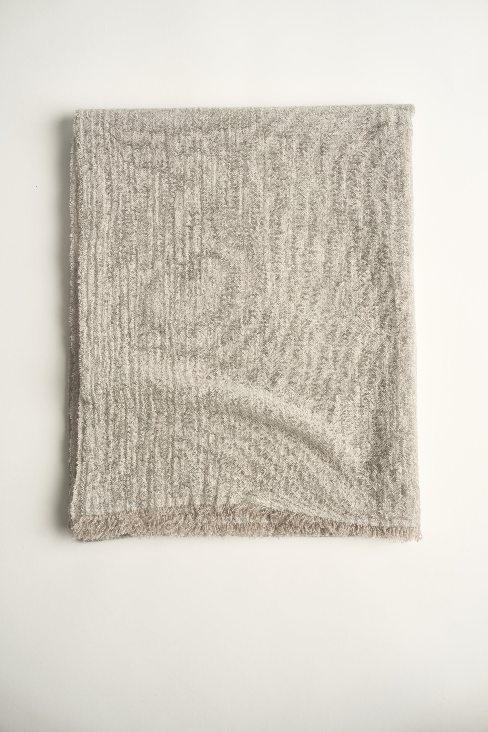 A natural light colour cashmere throw with a soft, airy weave, displayed on a plain background.
