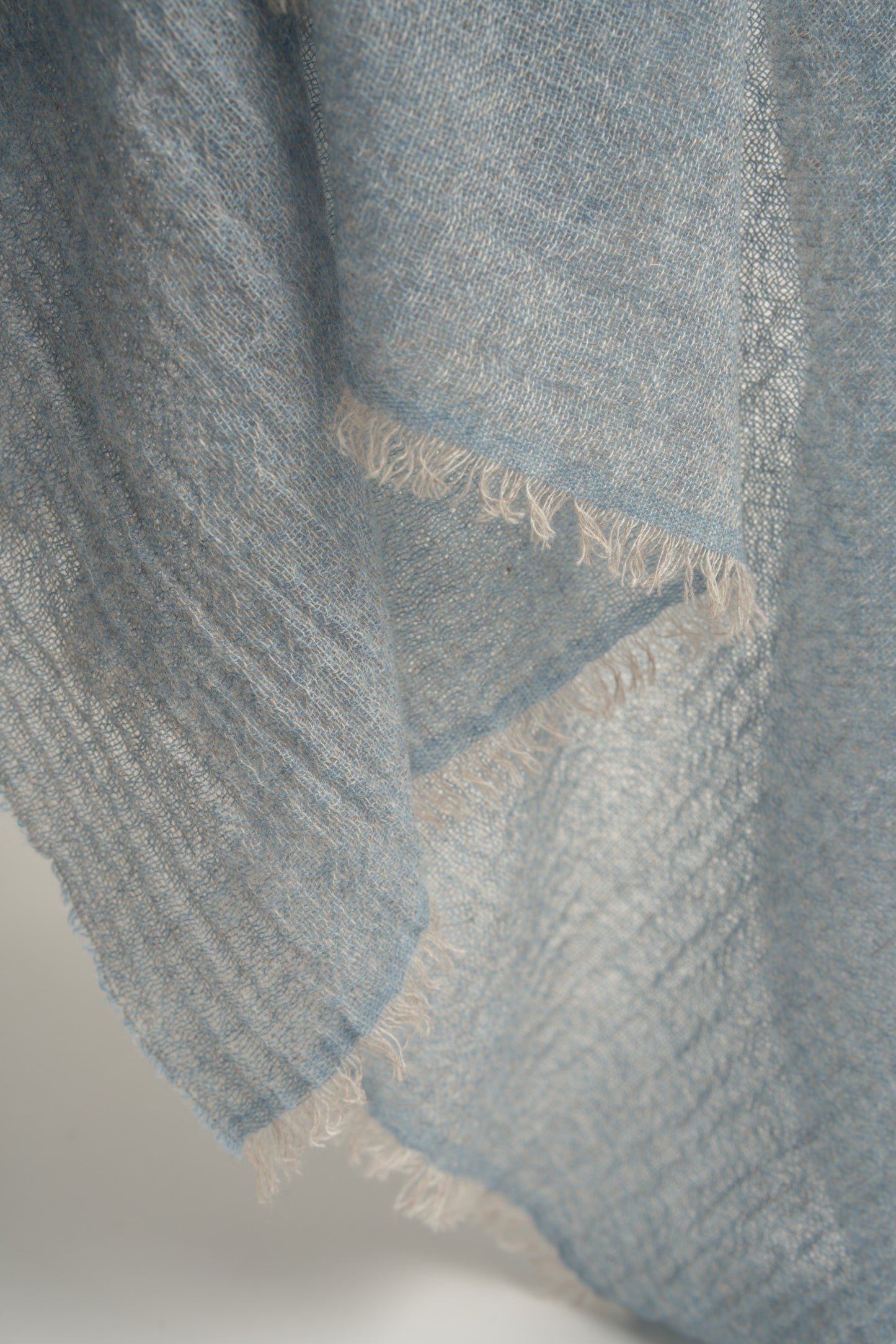 A close up of a soft blue cashmere throw with a soft, airy weave.