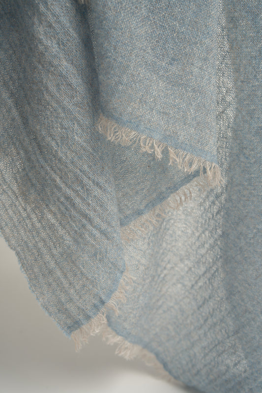 A close up of a soft blue cashmere throw with a soft, airy weave.