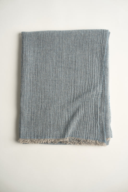 A soft blue cashmere throw with a soft, airy weave, displayed on a plain background.