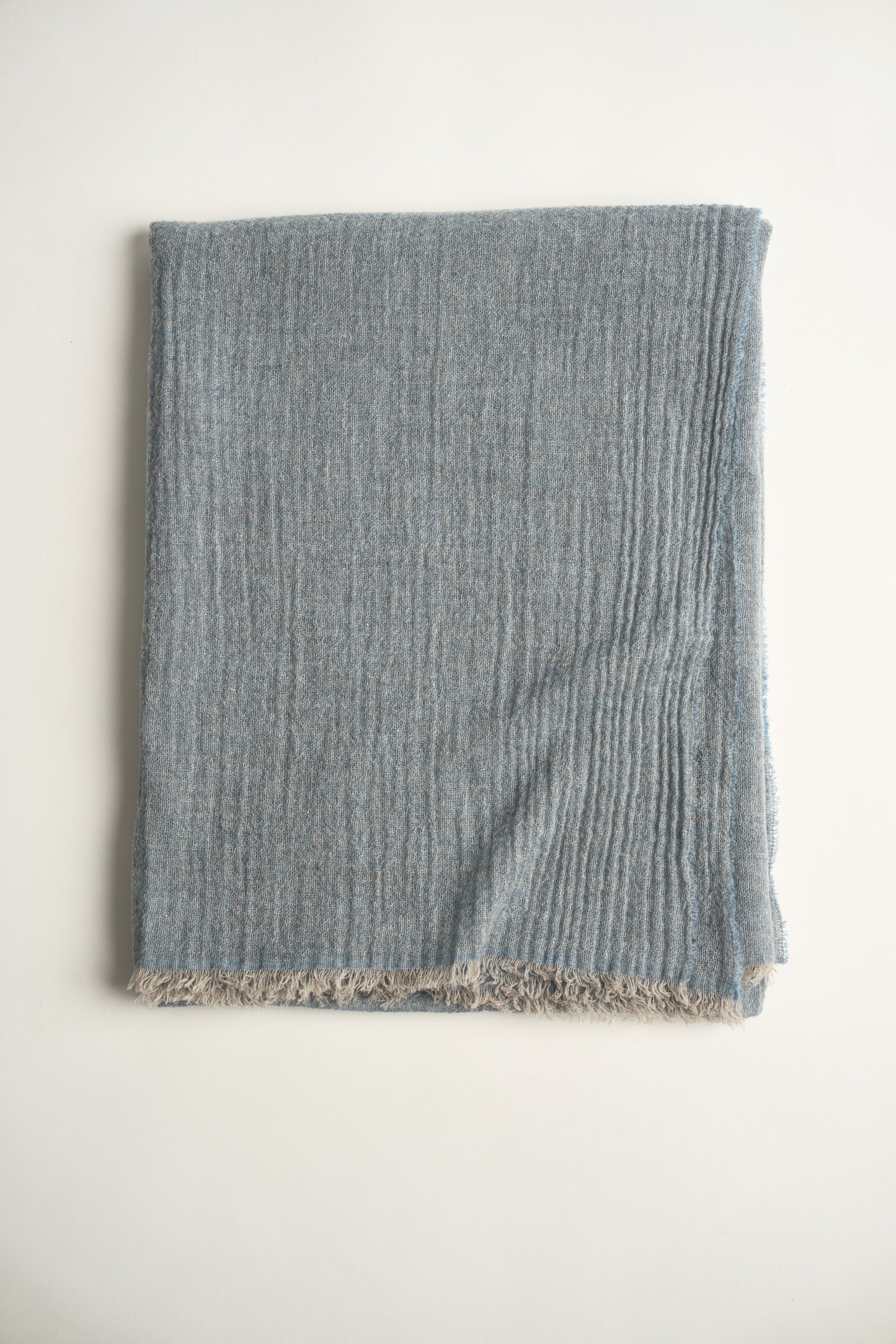 A folded light blue throw on a white background