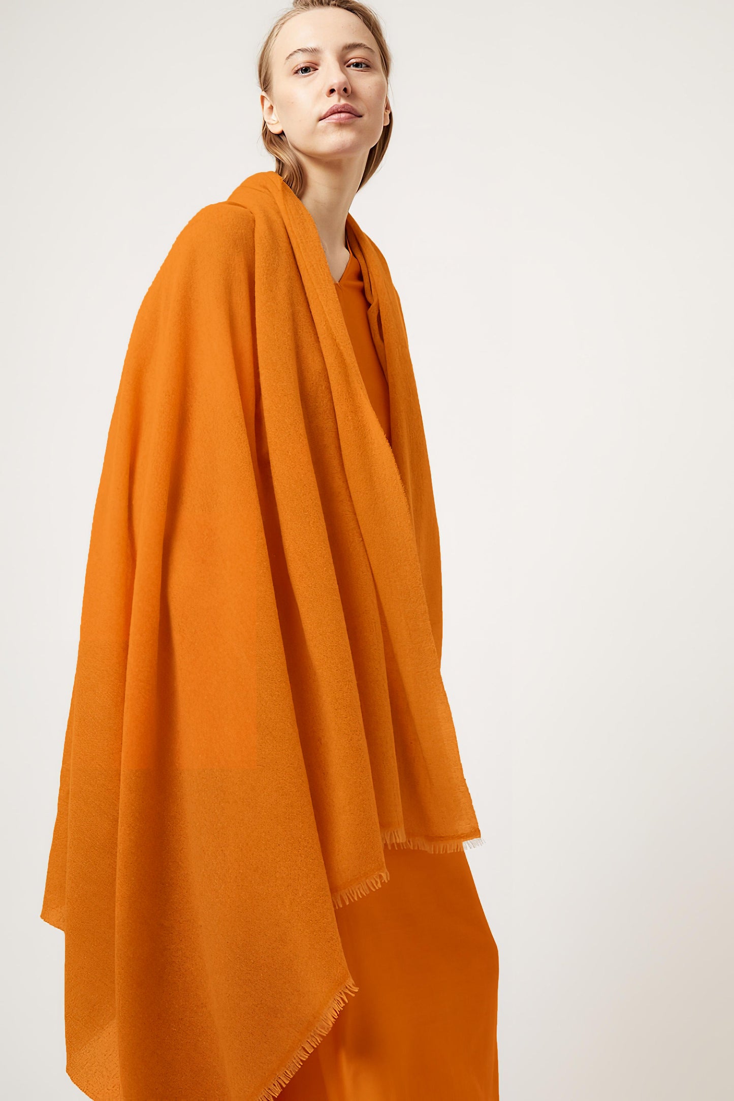 A gold esra throw draped over a models shoulders