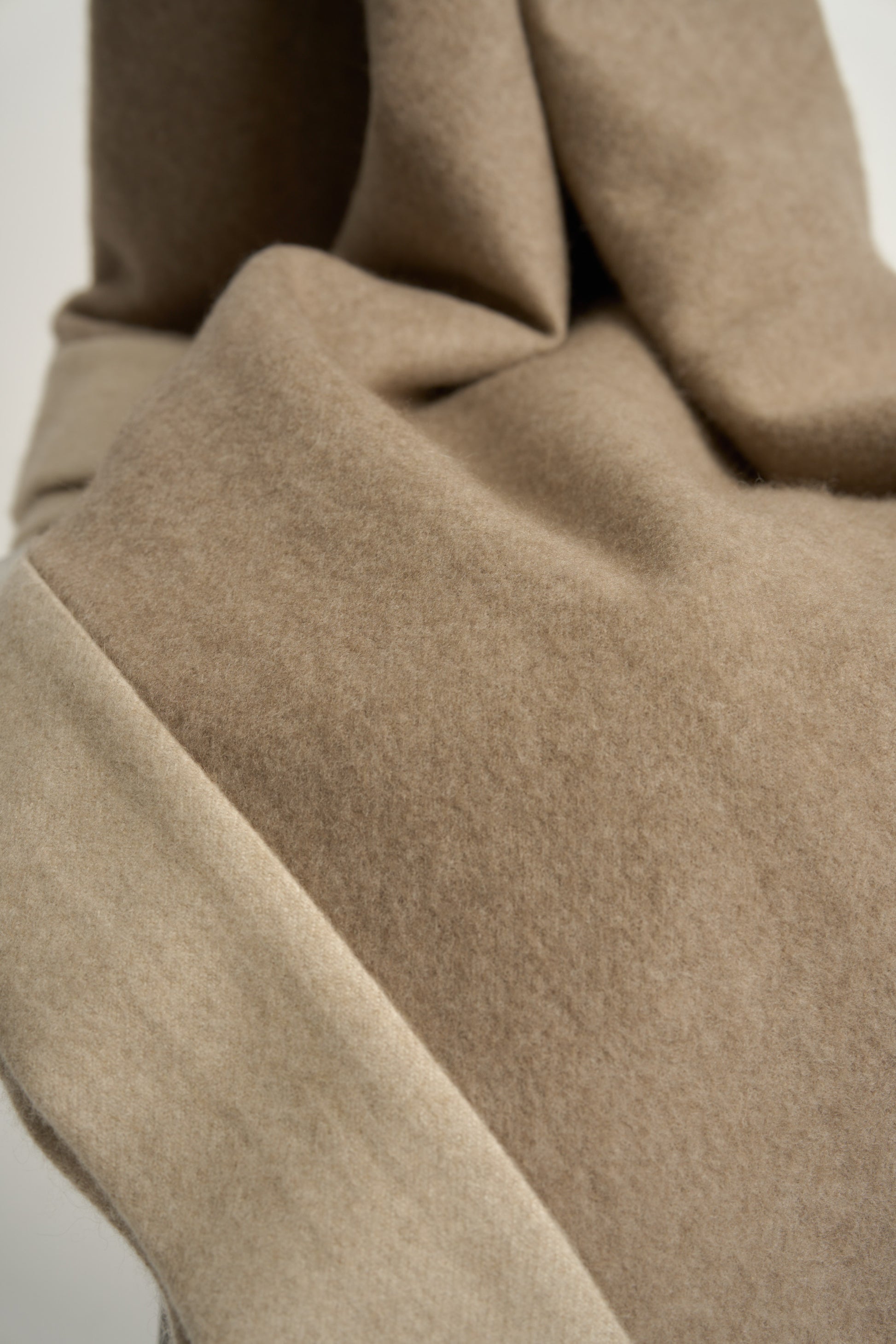A king-size bedspread in taupe & beige, draped over a chair with a neutral background.
