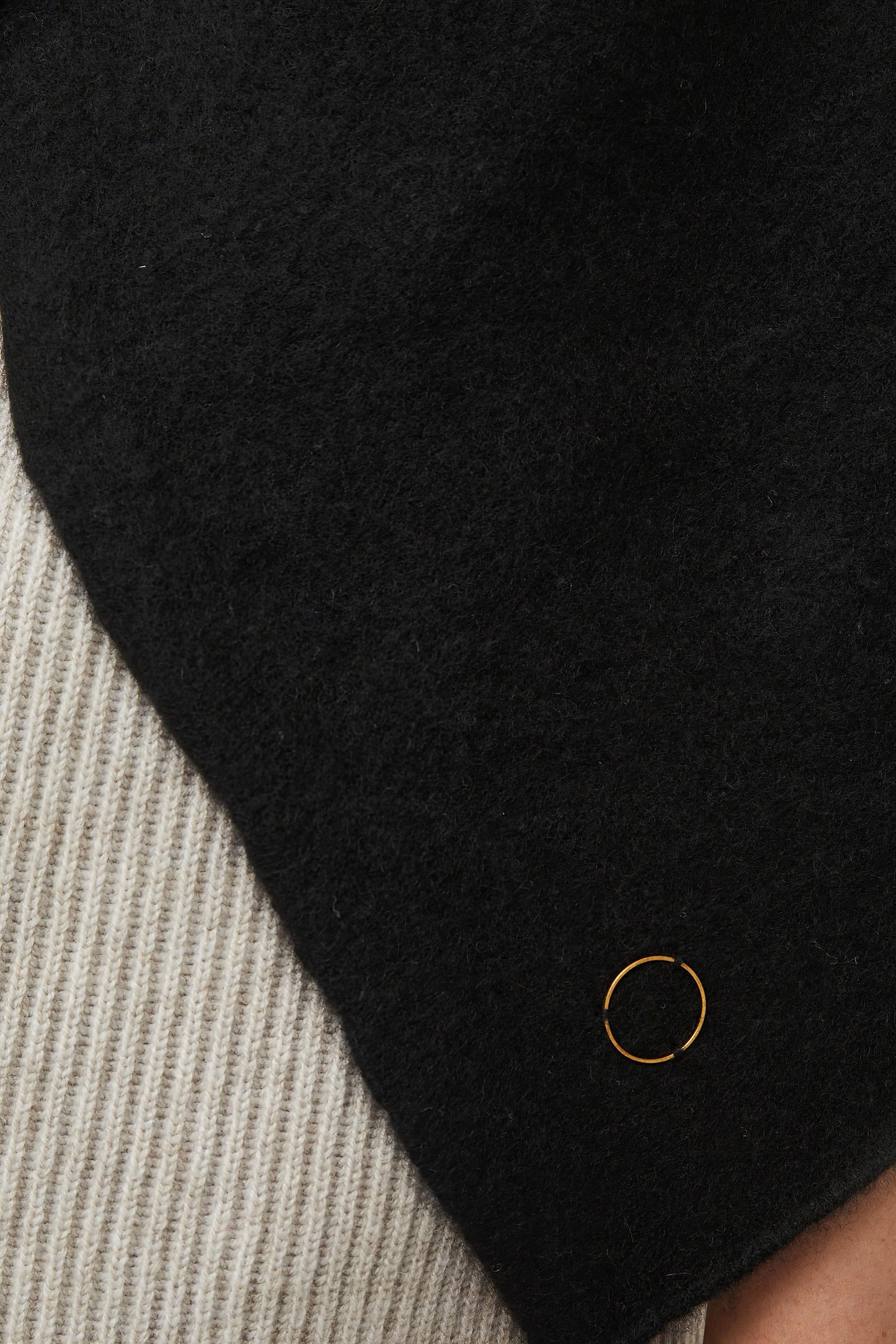 This image features the Feltra Shawl, an elegant and warm accessory made from felted cashmere, emphasizing pure simplicity and luxury. The shawl is presented in a deep, rich black color, enhancing its sophisticated and sleek appearance.