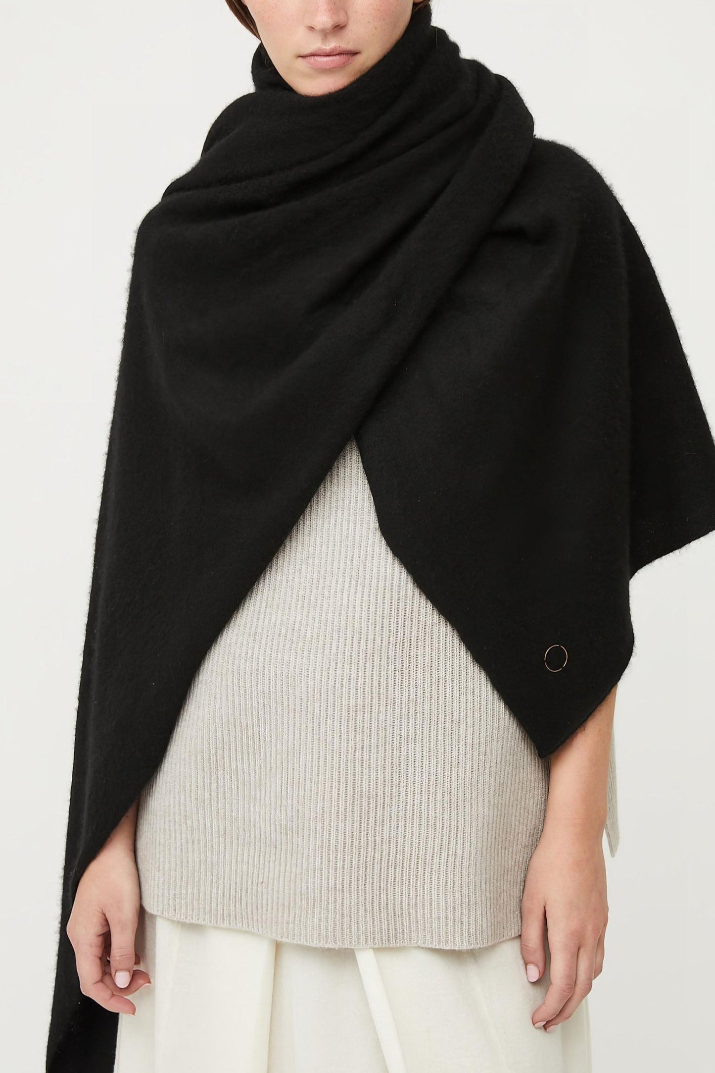 This image features the Feltra Shawl, an elegant and warm accessory made from felted cashmere, emphasizing pure simplicity and luxury. The shawl is presented in a deep, rich black color, enhancing its sophisticated and sleek appearance.