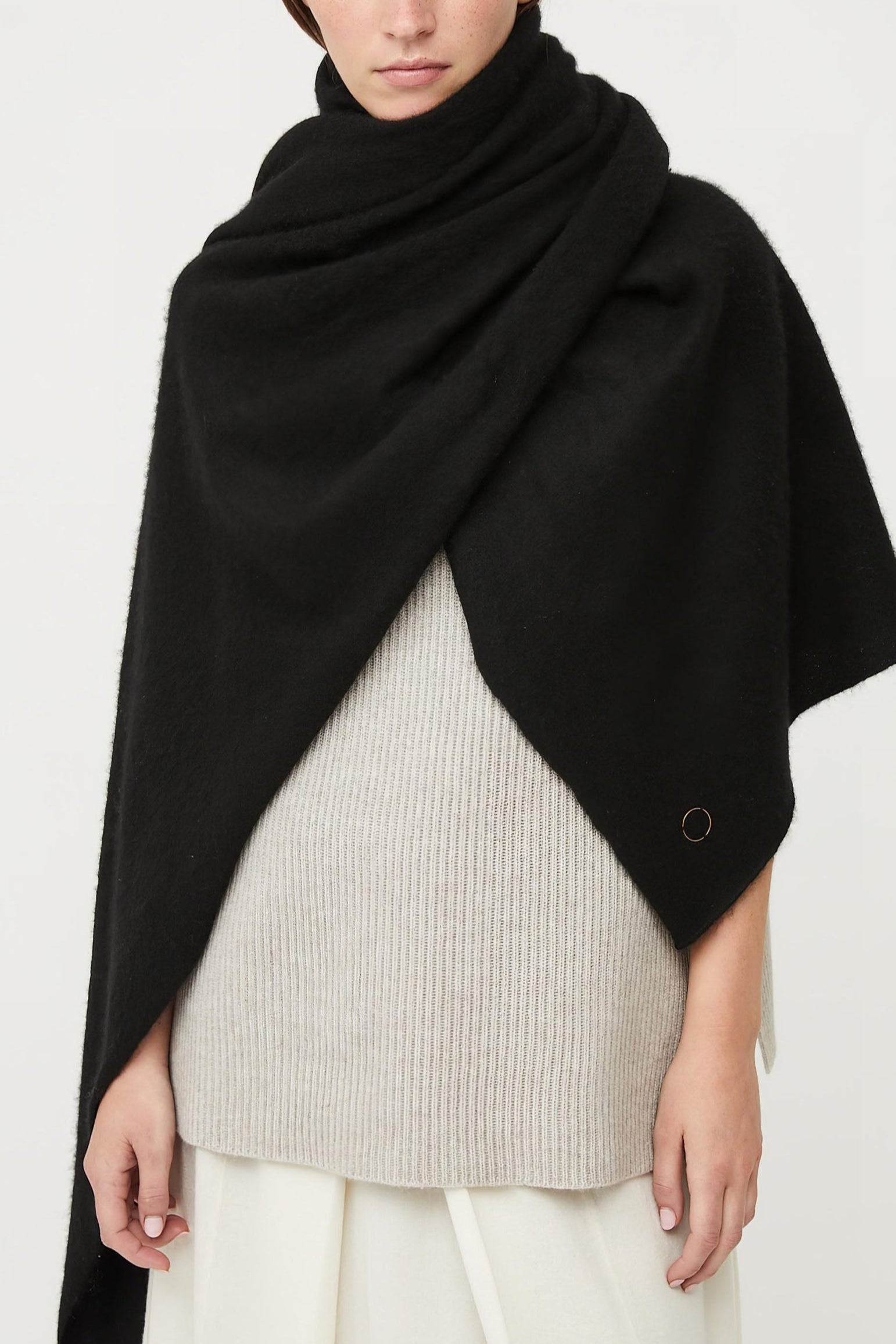 This image features the Feltra Shawl, an elegant and warm accessory made from felted cashmere, emphasizing pure simplicity and luxury. The shawl is presented in a deep, rich black color, enhancing its sophisticated and sleek appearance.