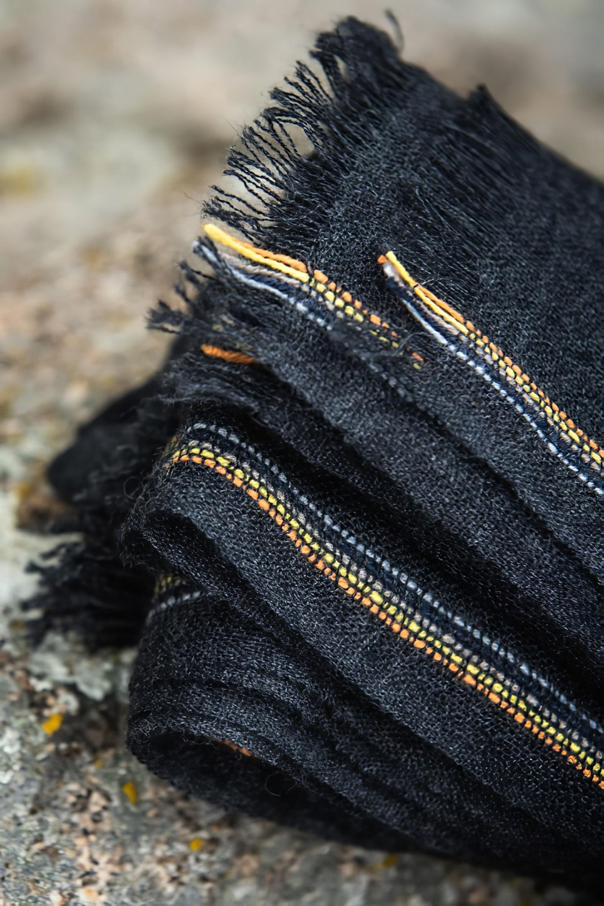 An image of a folded charcoal cashmere throw with contrast stripes and fringes.