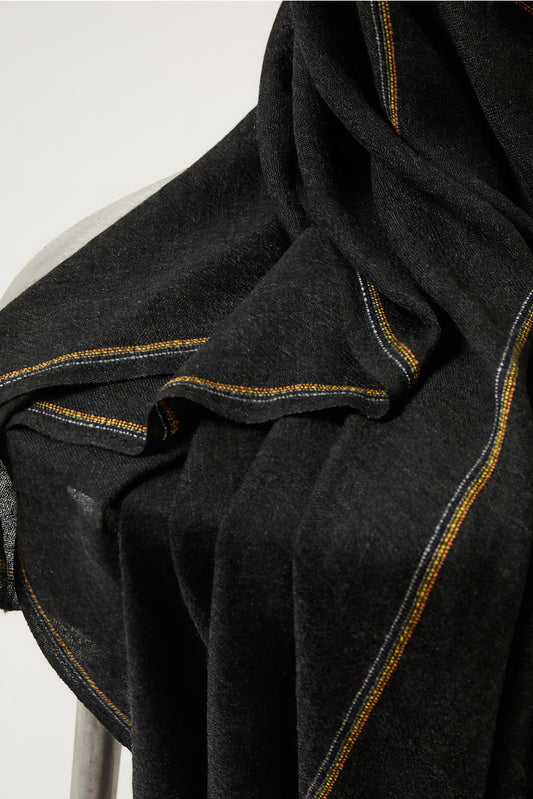 An image of a folded charcoal cashmere throw with contrast stripes and fringes.