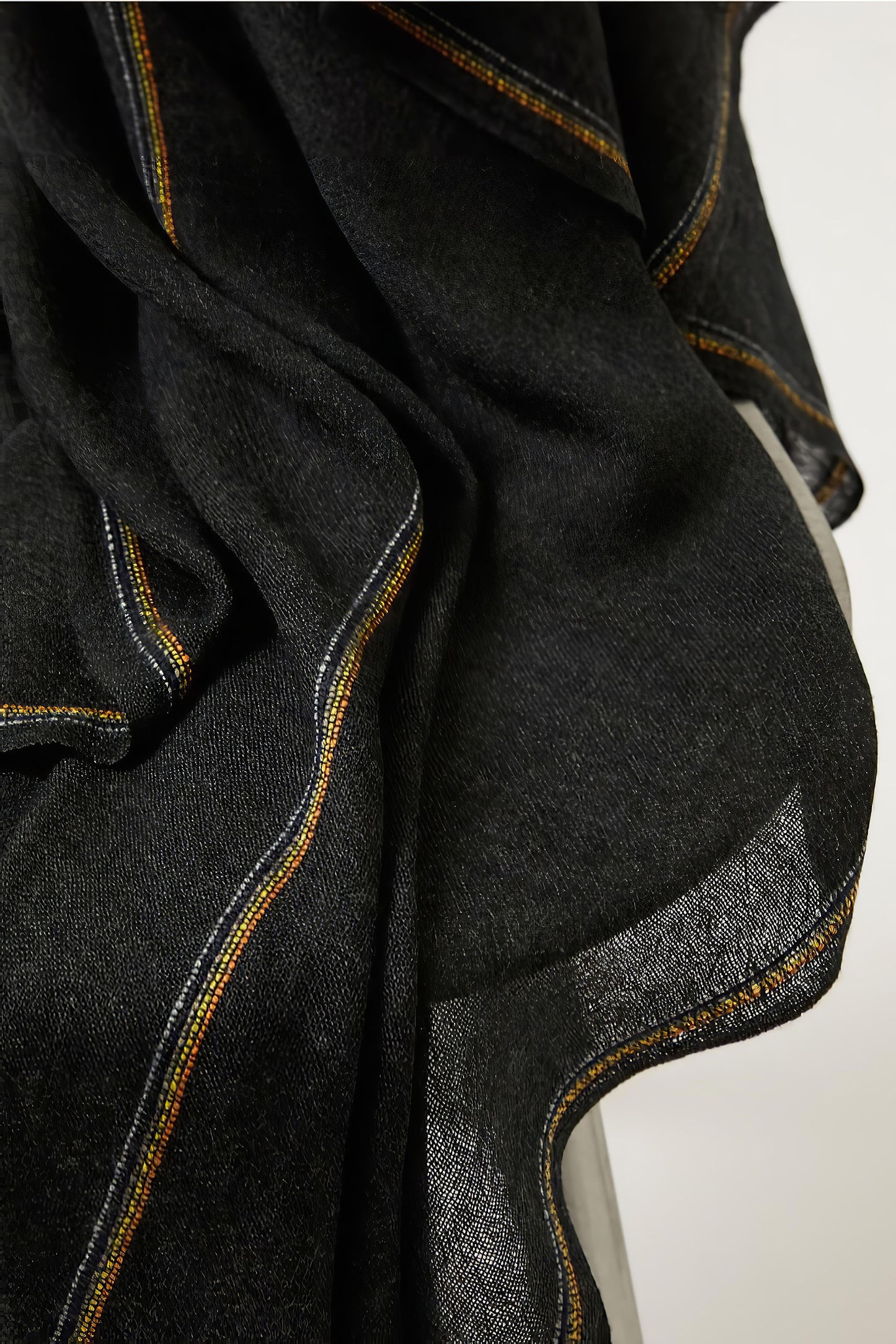 An image of a folded charcoal cashmere throw with contrast stripes and fringes.