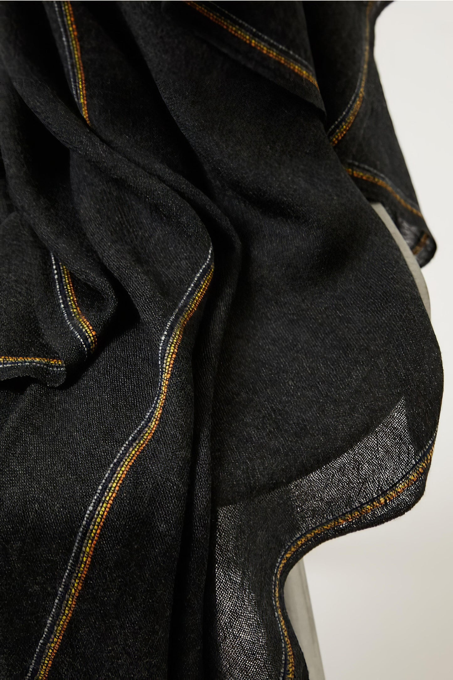 Close-up of a charcoal cashmere throw with contrast stripes and fringes.