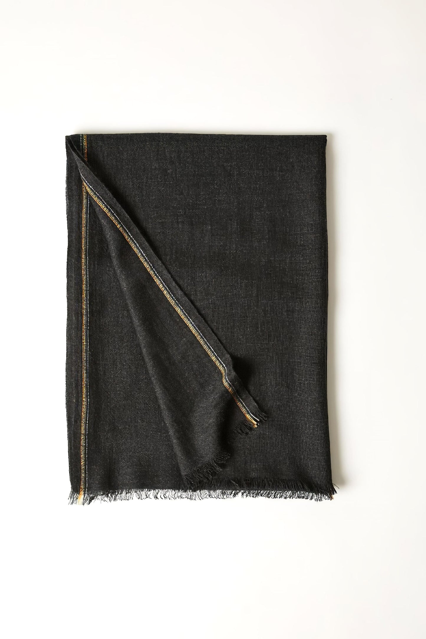 An image of a folded charcoal cashmere throw with contrast stripes and fringes.