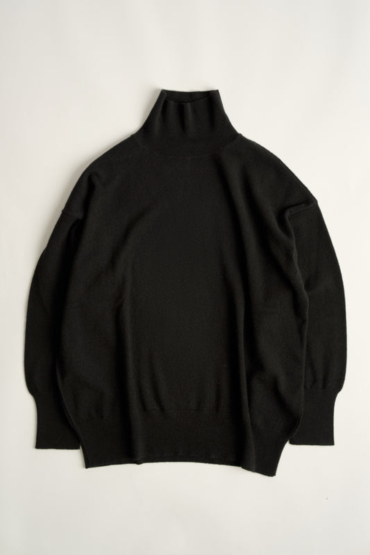 This image features the Kotto Sweater, characterized by its high-neck design and relaxed fit. The sweater is crafted from a classic jersey knit, showcased in a soft, black color.