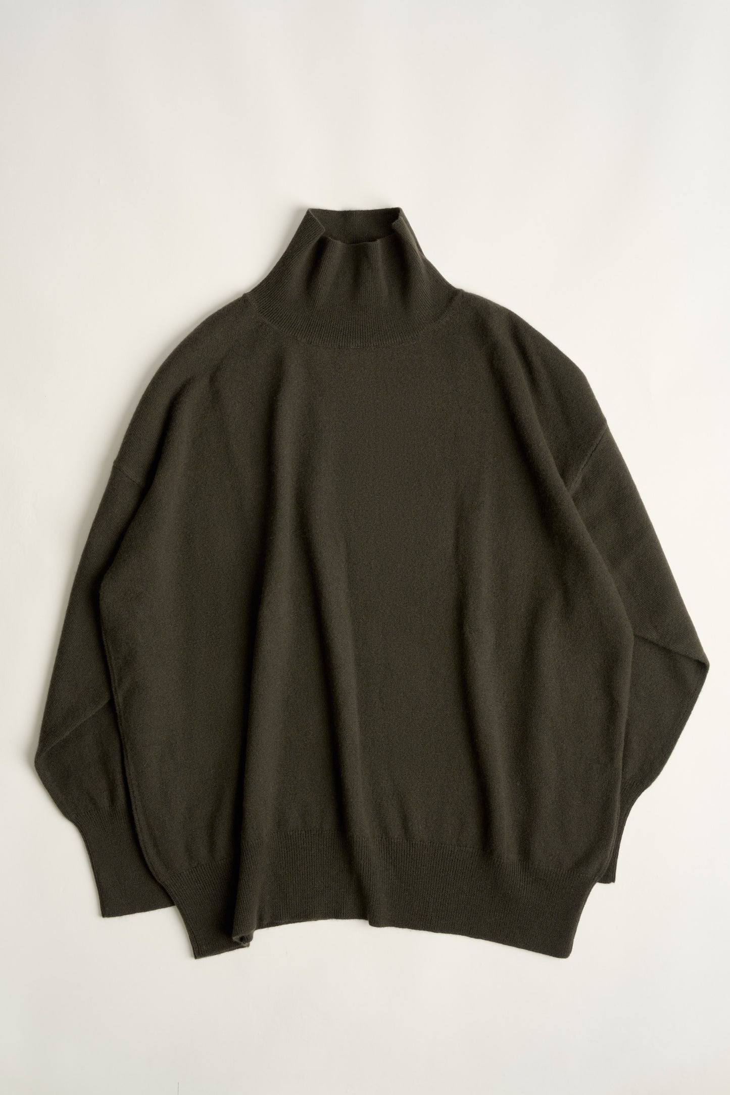 This image features the Kotto Sweater, characterized by its high-neck design and relaxed fit. The sweater is crafted from a classic jersey knit, showcased in a soft, forest color.