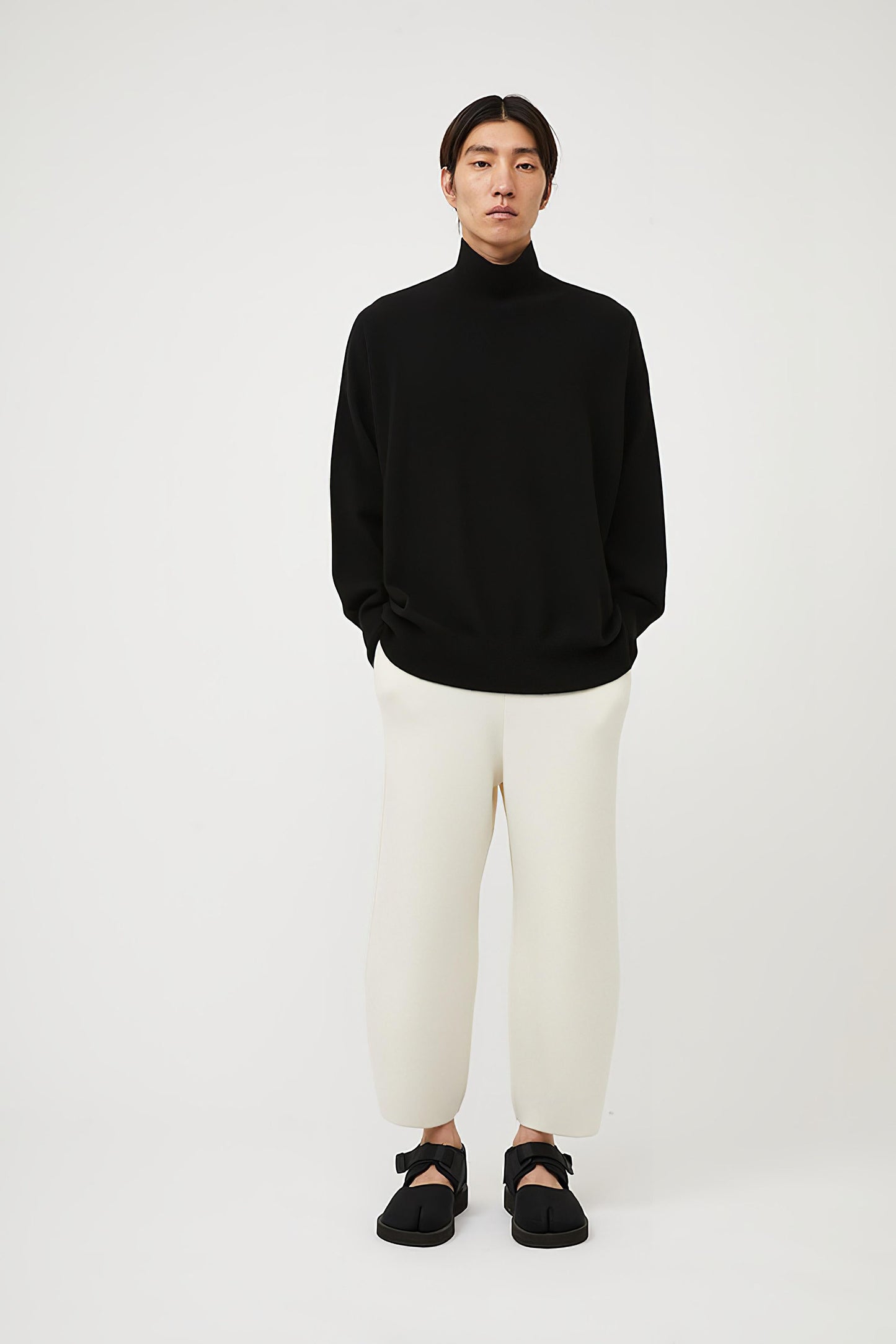 This image features the Kotto Sweater, characterized by its high-neck design and relaxed fit. The sweater is crafted from a classic jersey knit, showcased in a soft, black color.
