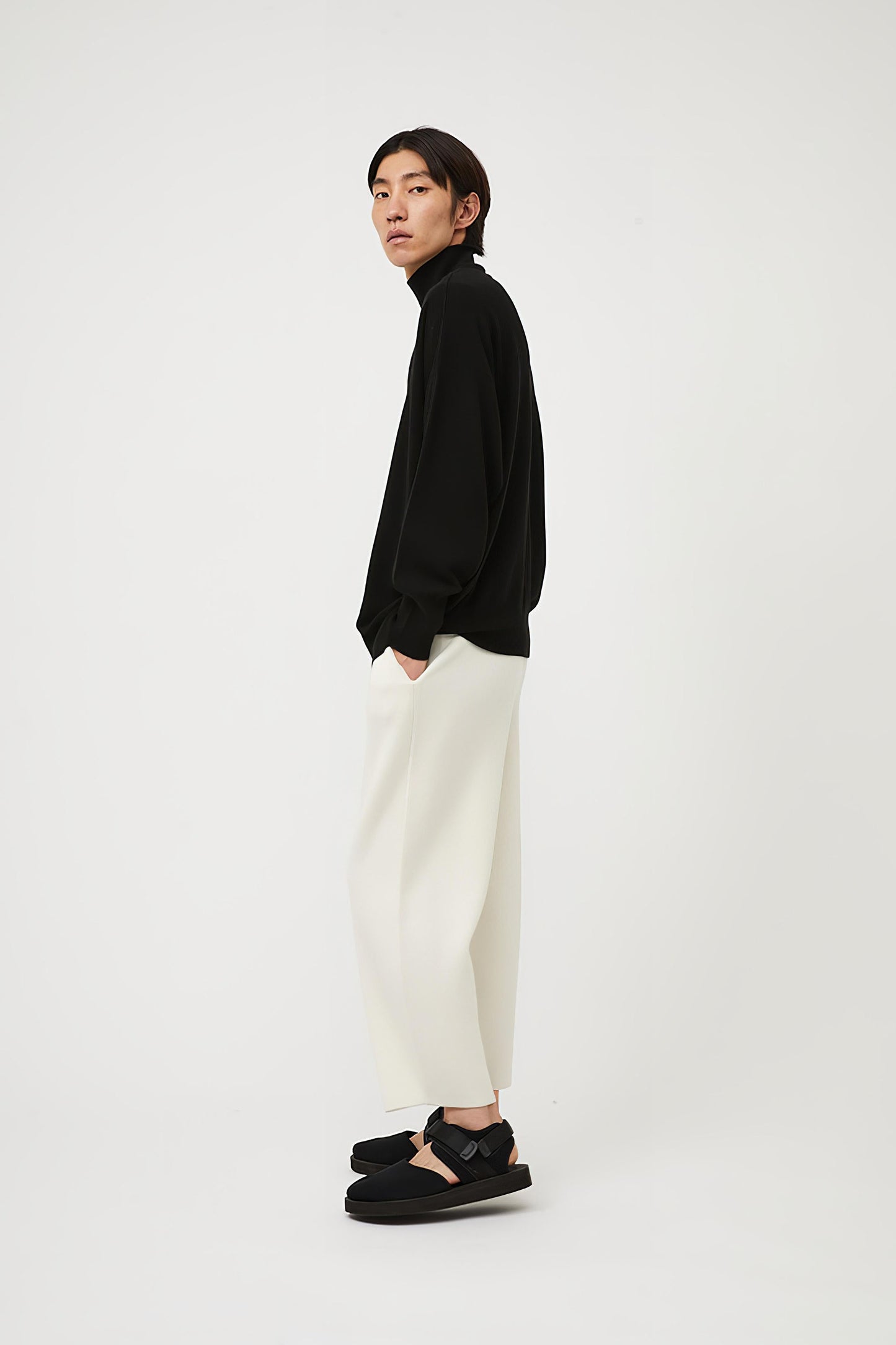 This image features the Kotto Sweater, characterized by its high-neck design and relaxed fit. The sweater is crafted from a classic jersey knit, showcased in a soft, black color.