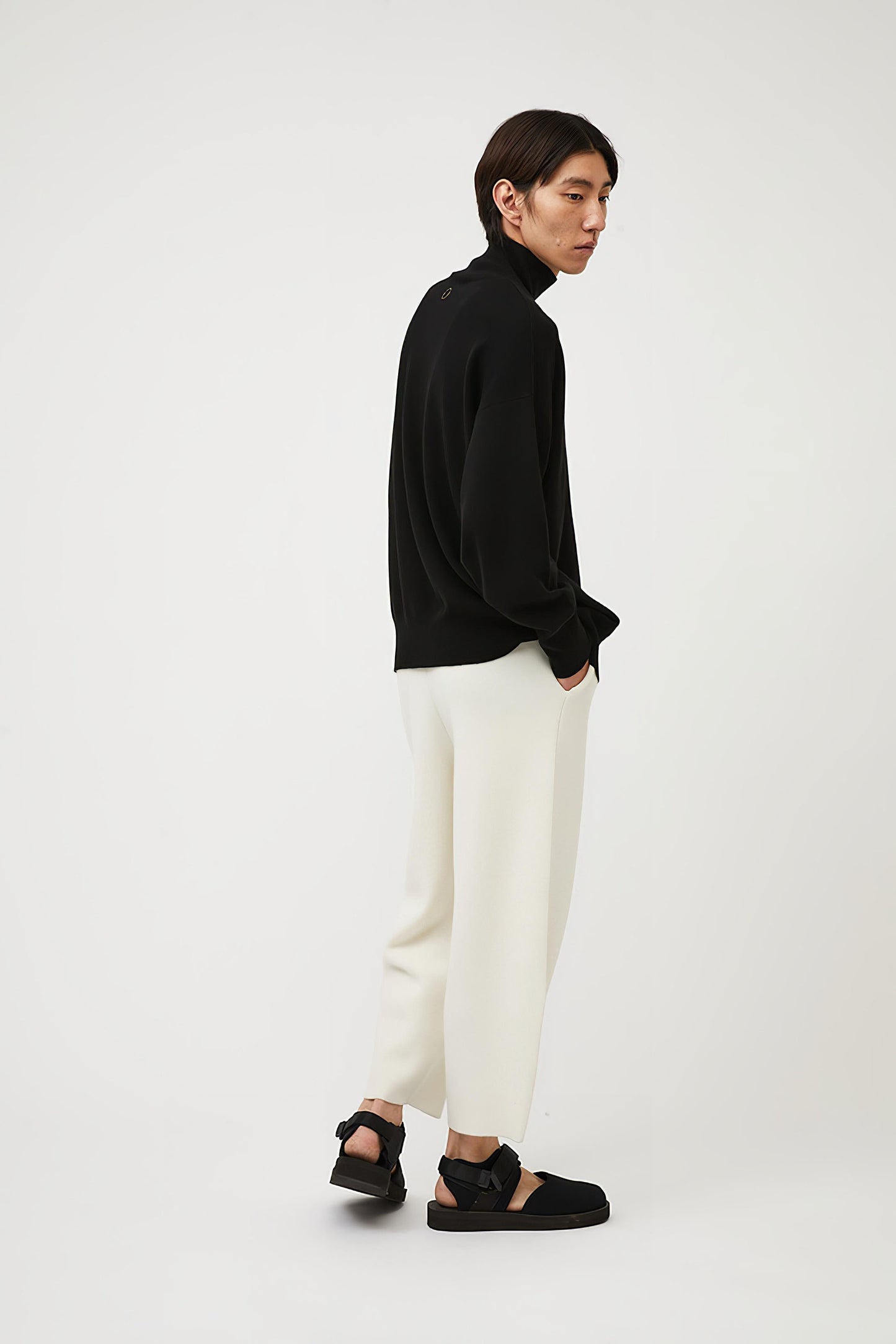 This image features the Kotto Sweater, characterized by its high-neck design and relaxed fit. The sweater is crafted from a classic jersey knit, showcased in a soft, black color.