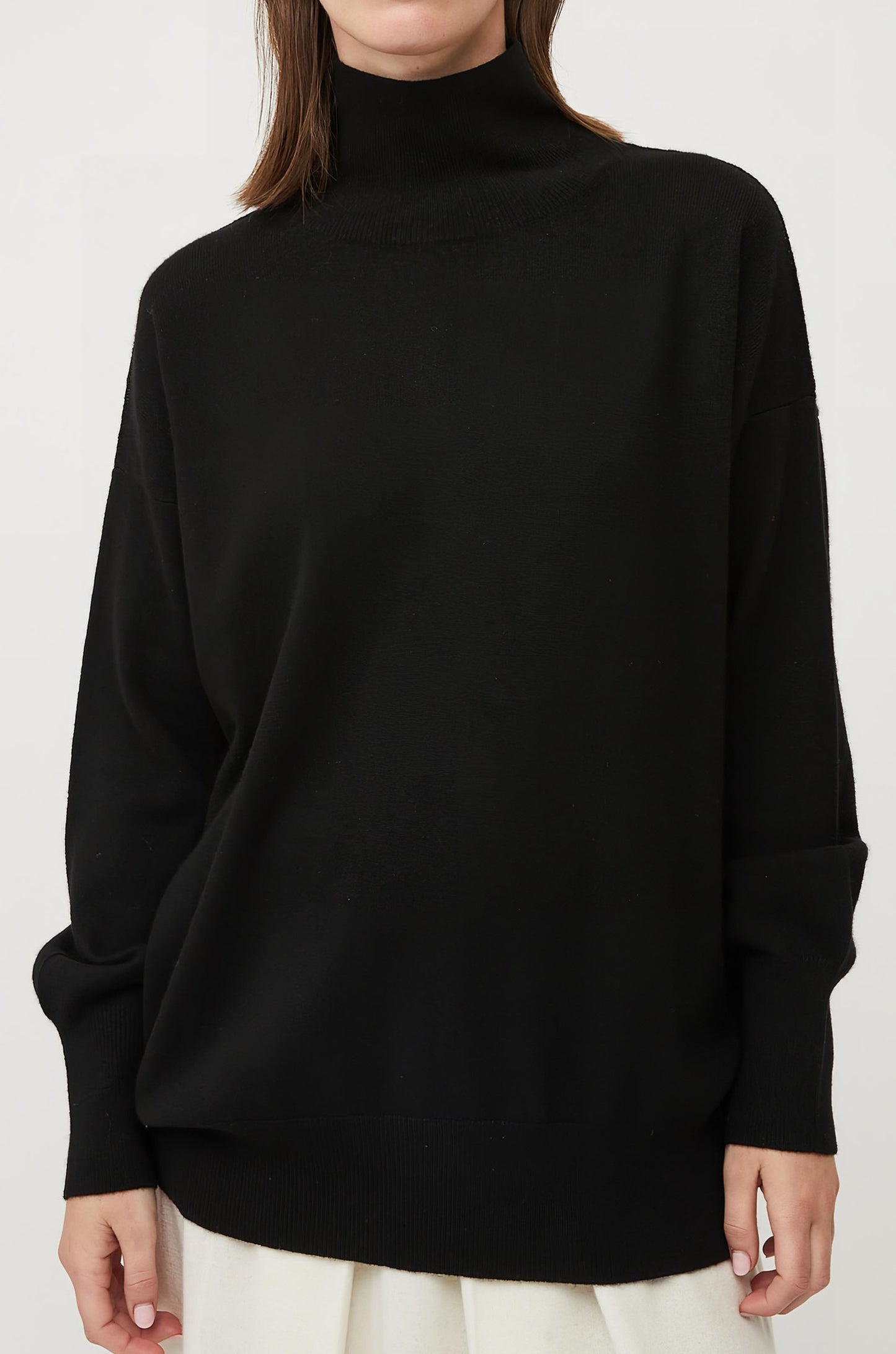 This image features the Kotto Sweater, highlighting its high-neck design and snug, comfortable fit. The sweater is presented in a classic, versatile black color, which enhances its elegant and timeless appeal.