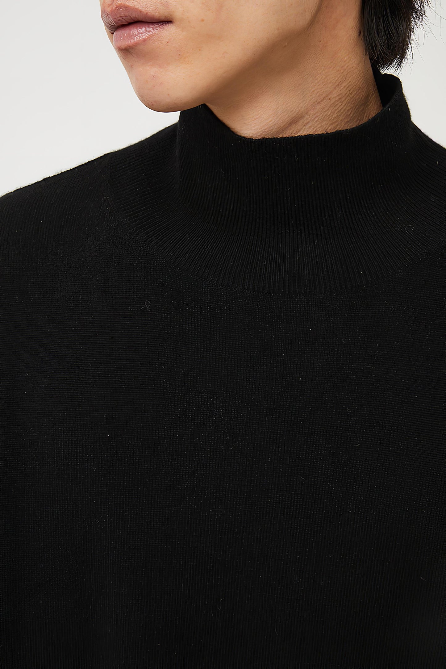 This image features the Kotto Sweater, characterized by its high-neck design and relaxed fit. The sweater is crafted from a classic jersey knit, showcased in a soft, black color.